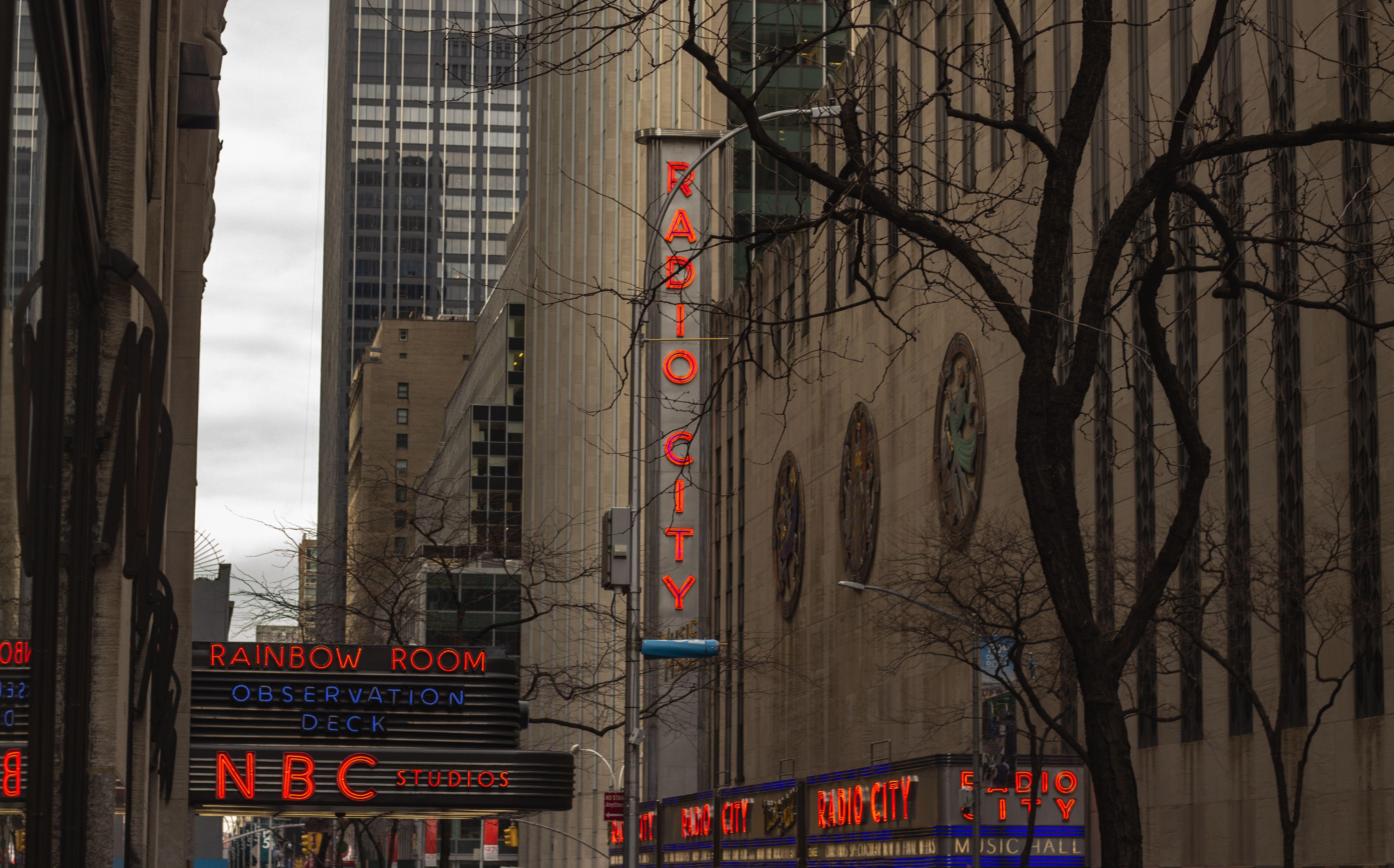 View of Radio City and NBC Studios signs in New York City featuring prominent neon lights.