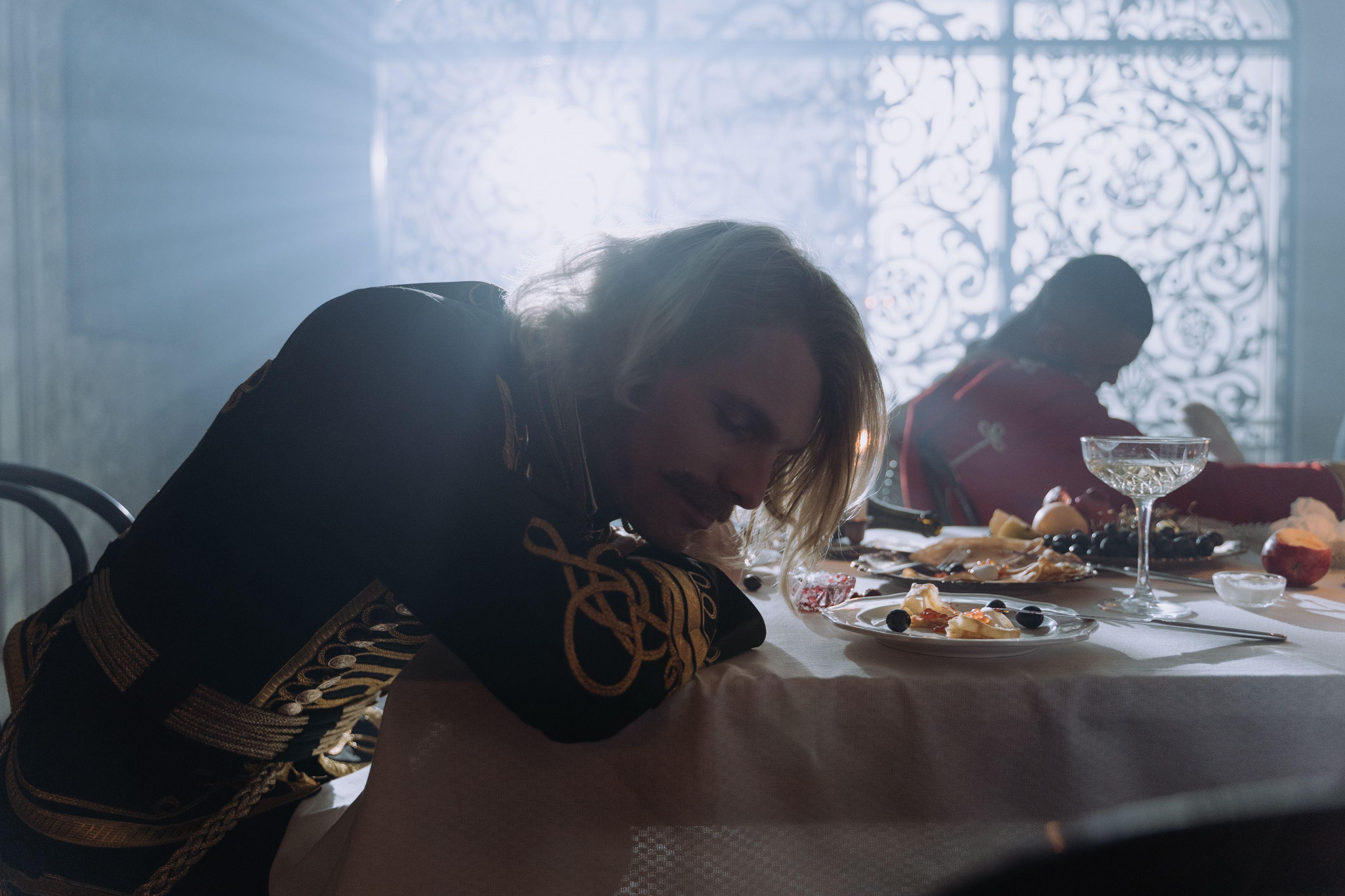 A 19th-century themed dinner setting with period costumes and sunlight streaming in.