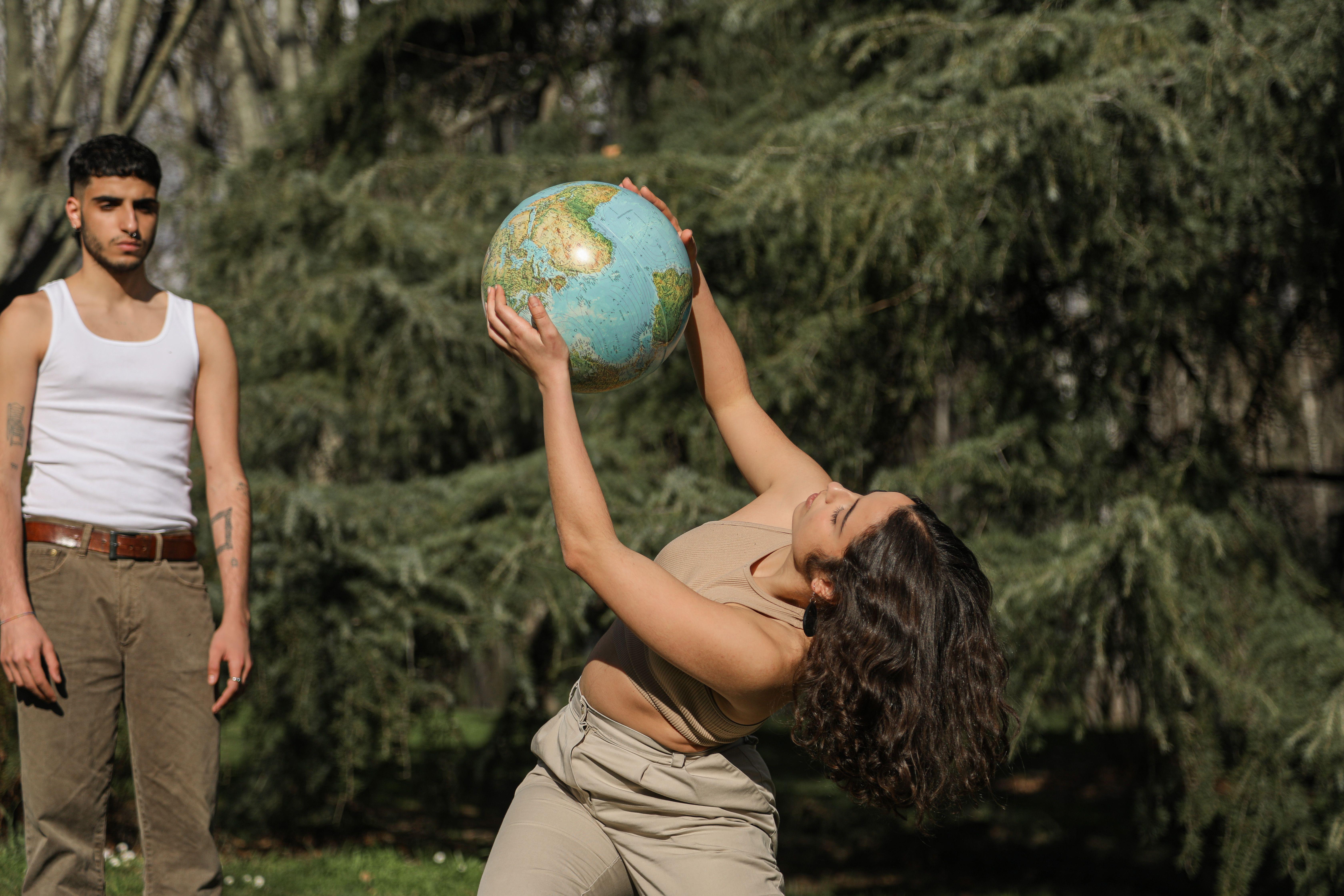 Two adults outdoors holding a globe, embracing global concepts and unity.
