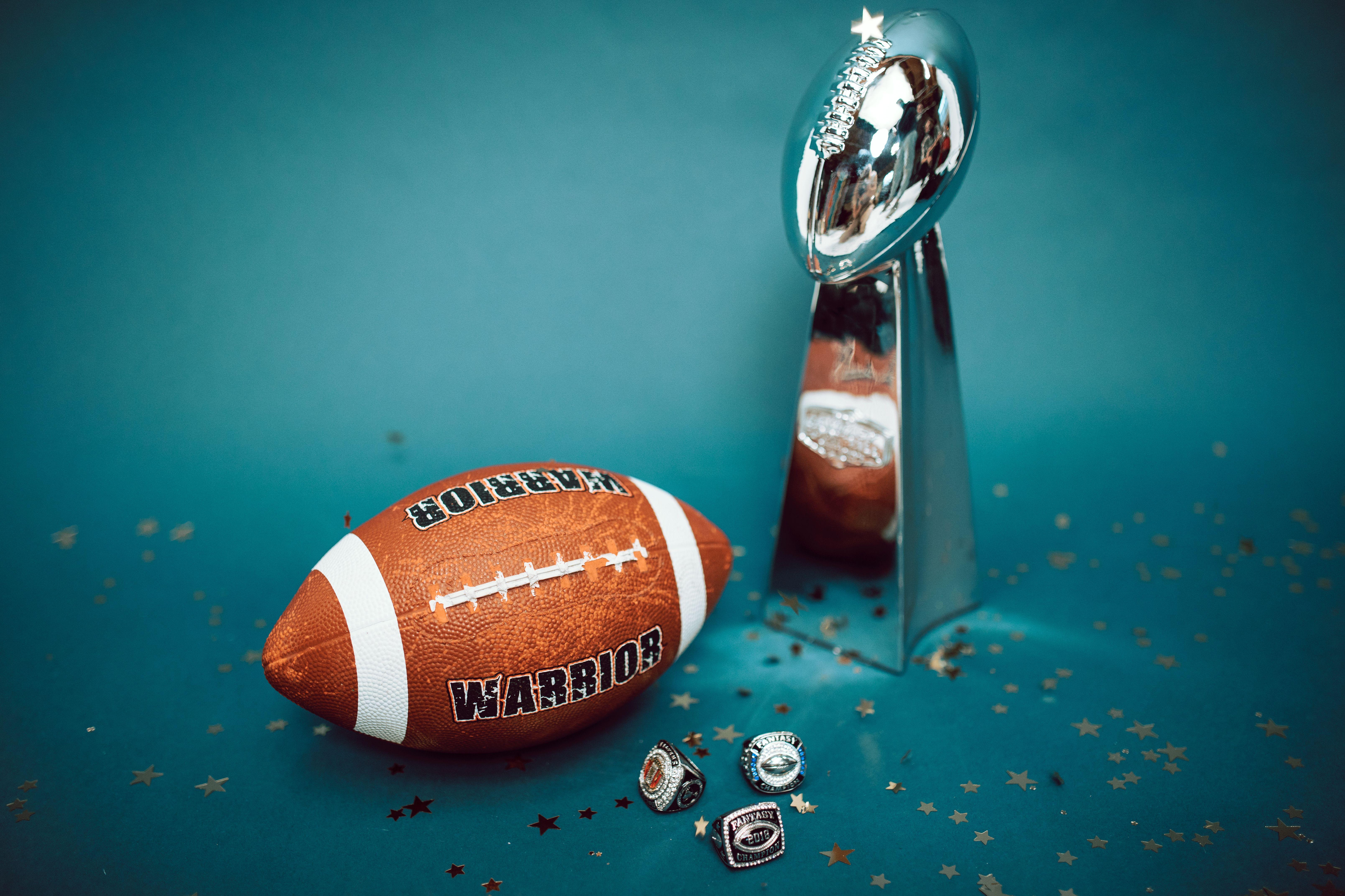 Football and trophy with championship rings on a celebratory background.