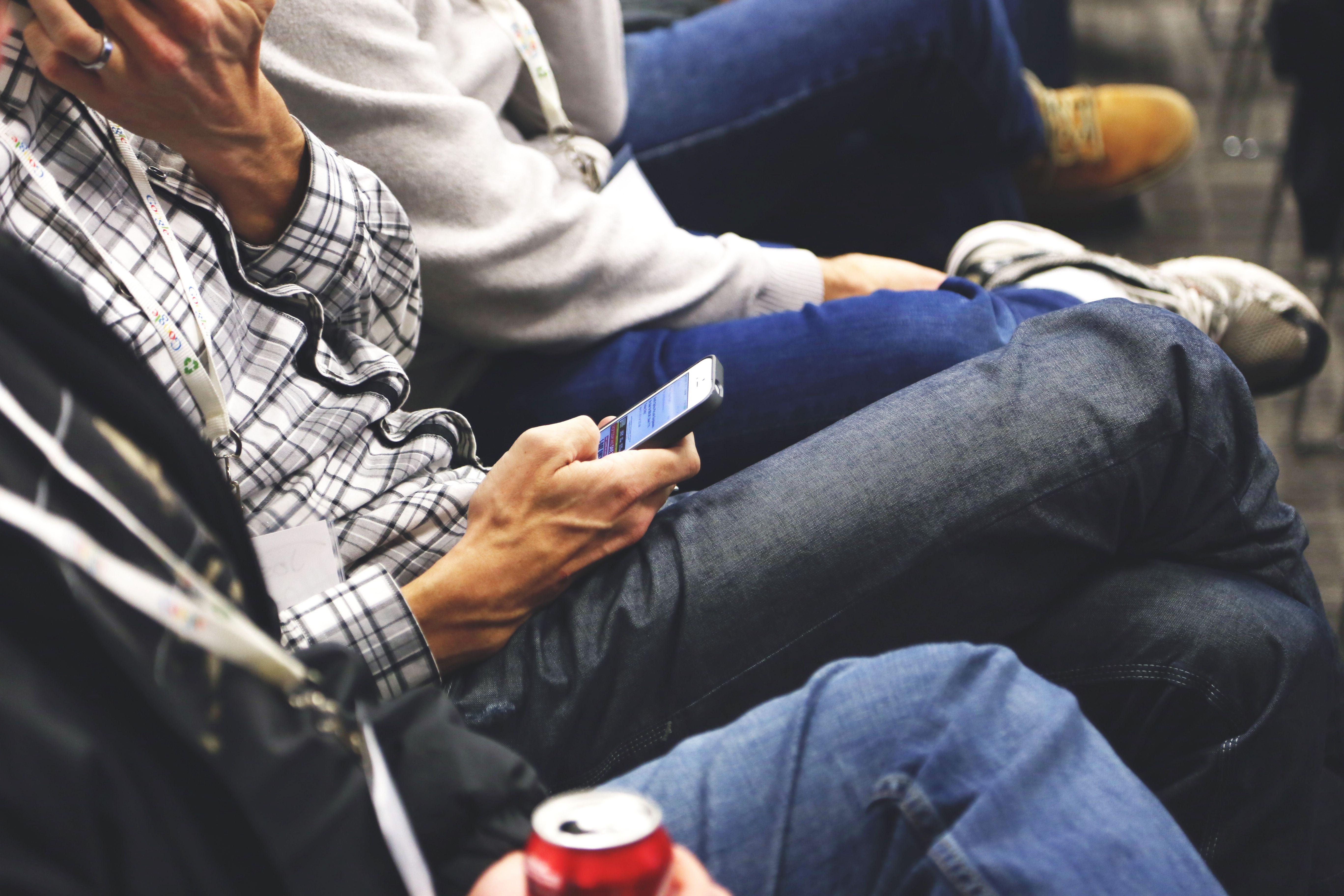 People sitting at a conference casually checking smartphones, communicating and networking.