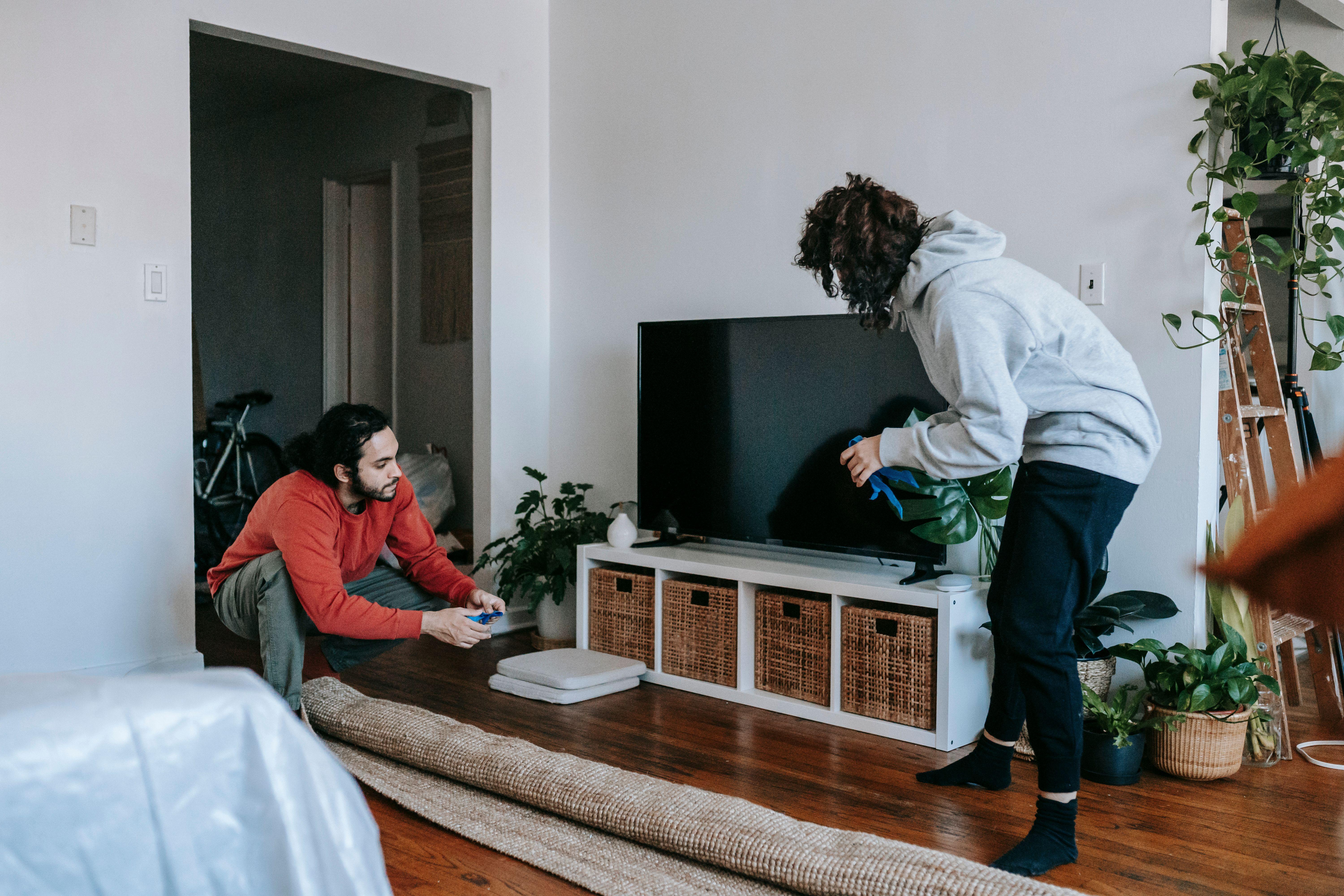 A couple organizing their living space with modern interior design elements and household items.