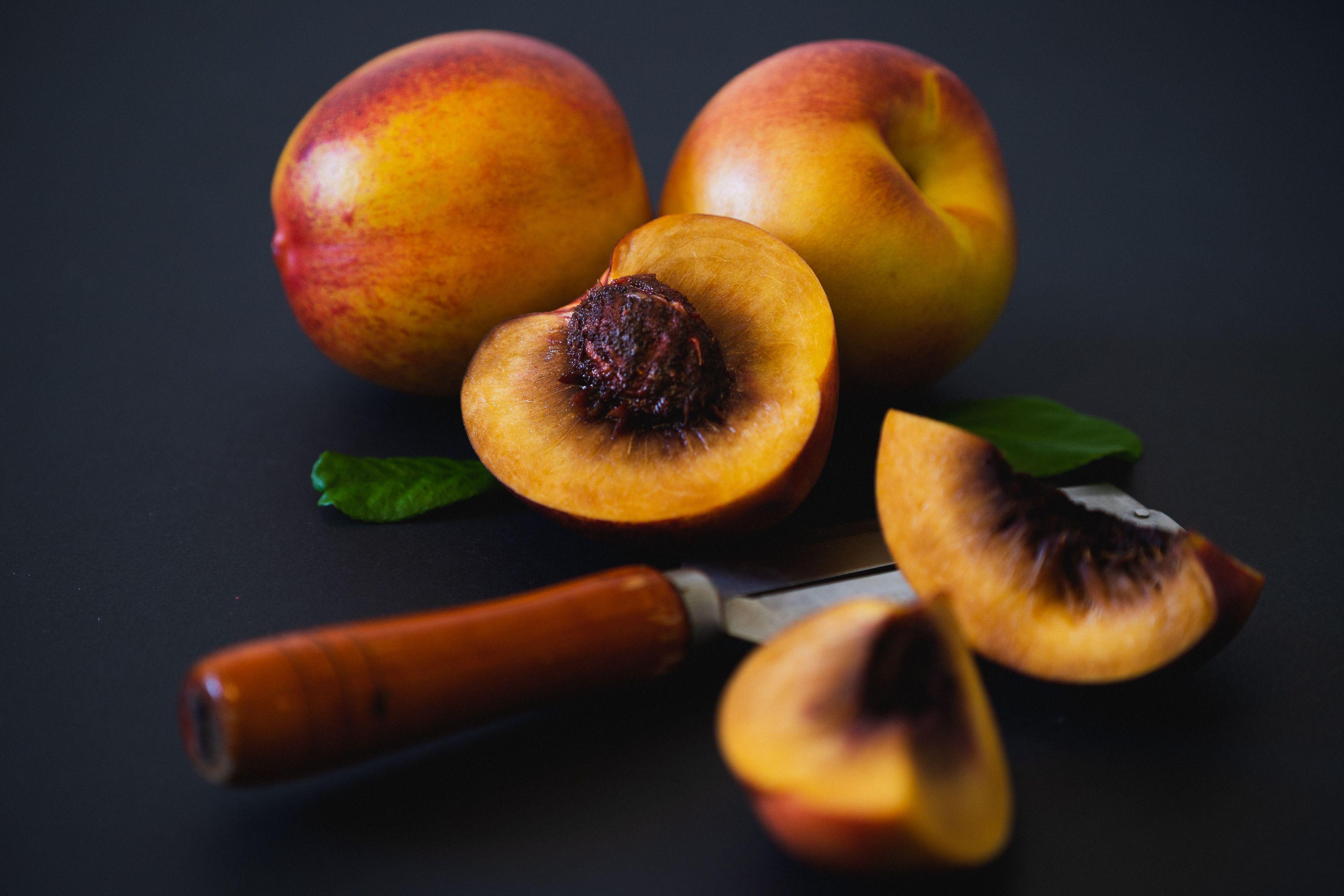 Vibrant fresh peaches sliced with a knife. Perfect for summer fruit concepts.