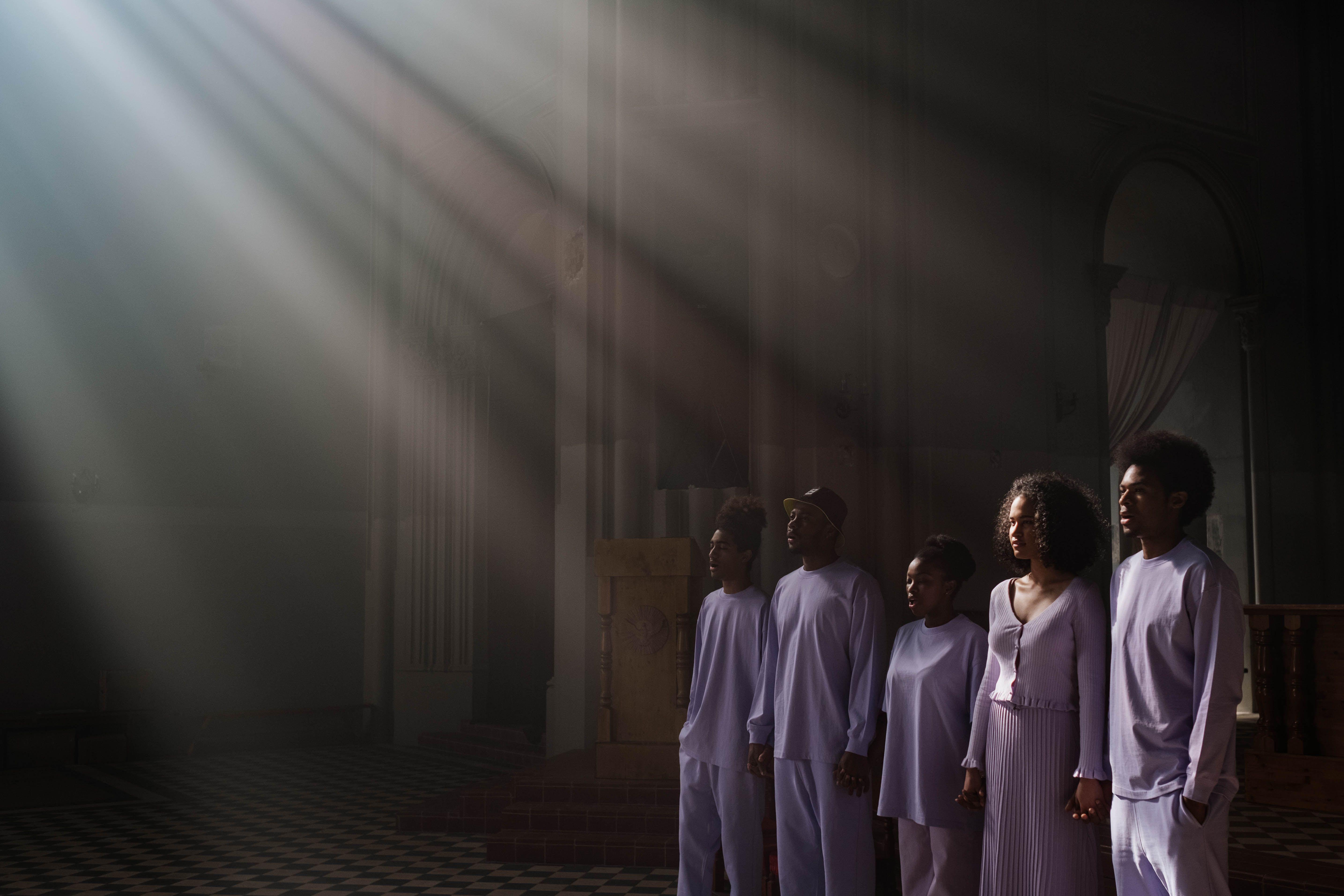 A choir of adults singing under sunbeams in a cathedral, creating a spiritual atmosphere.