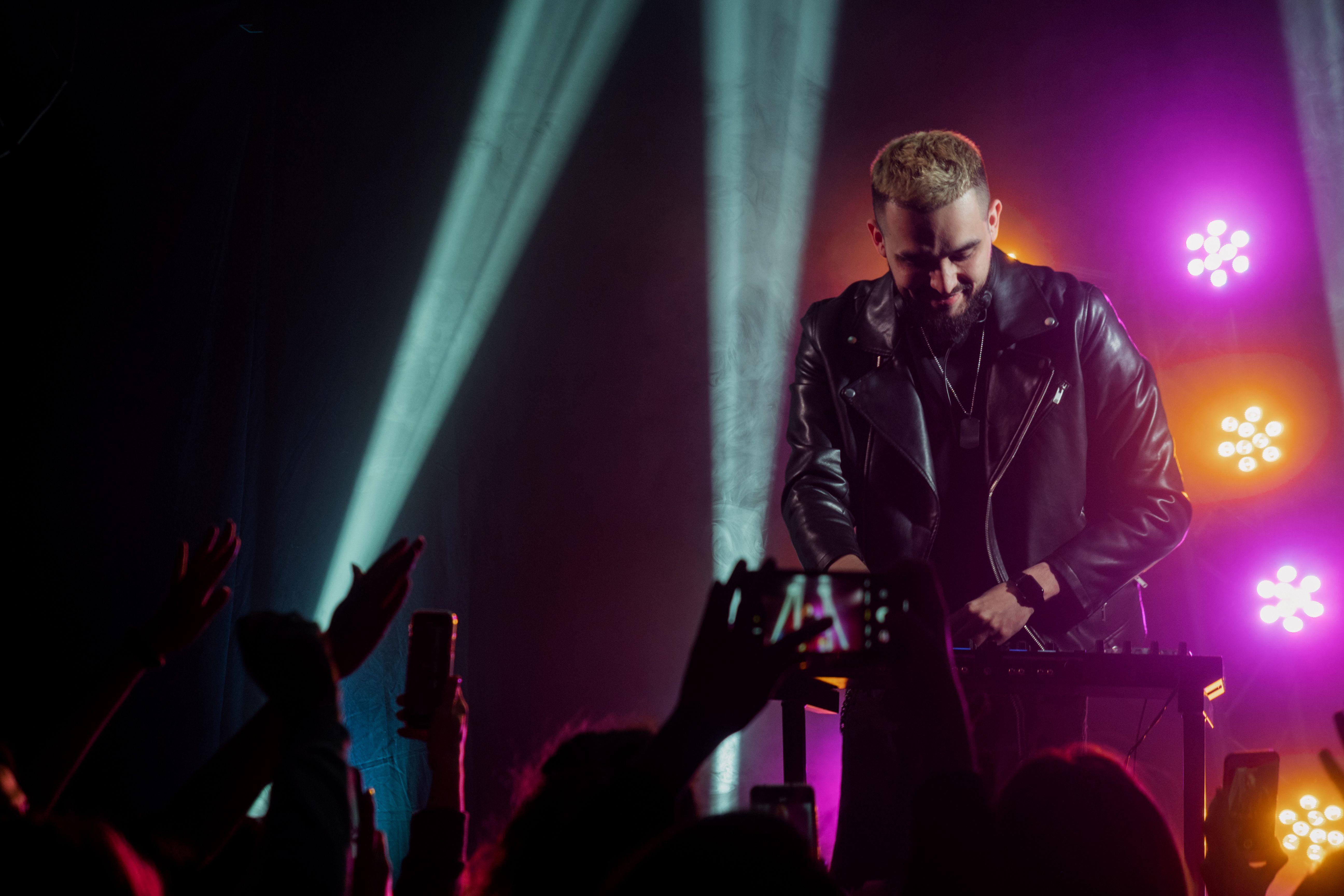 Live DJ performance with vibrant lighting, capturing the audience's excitement at an indoor concert.