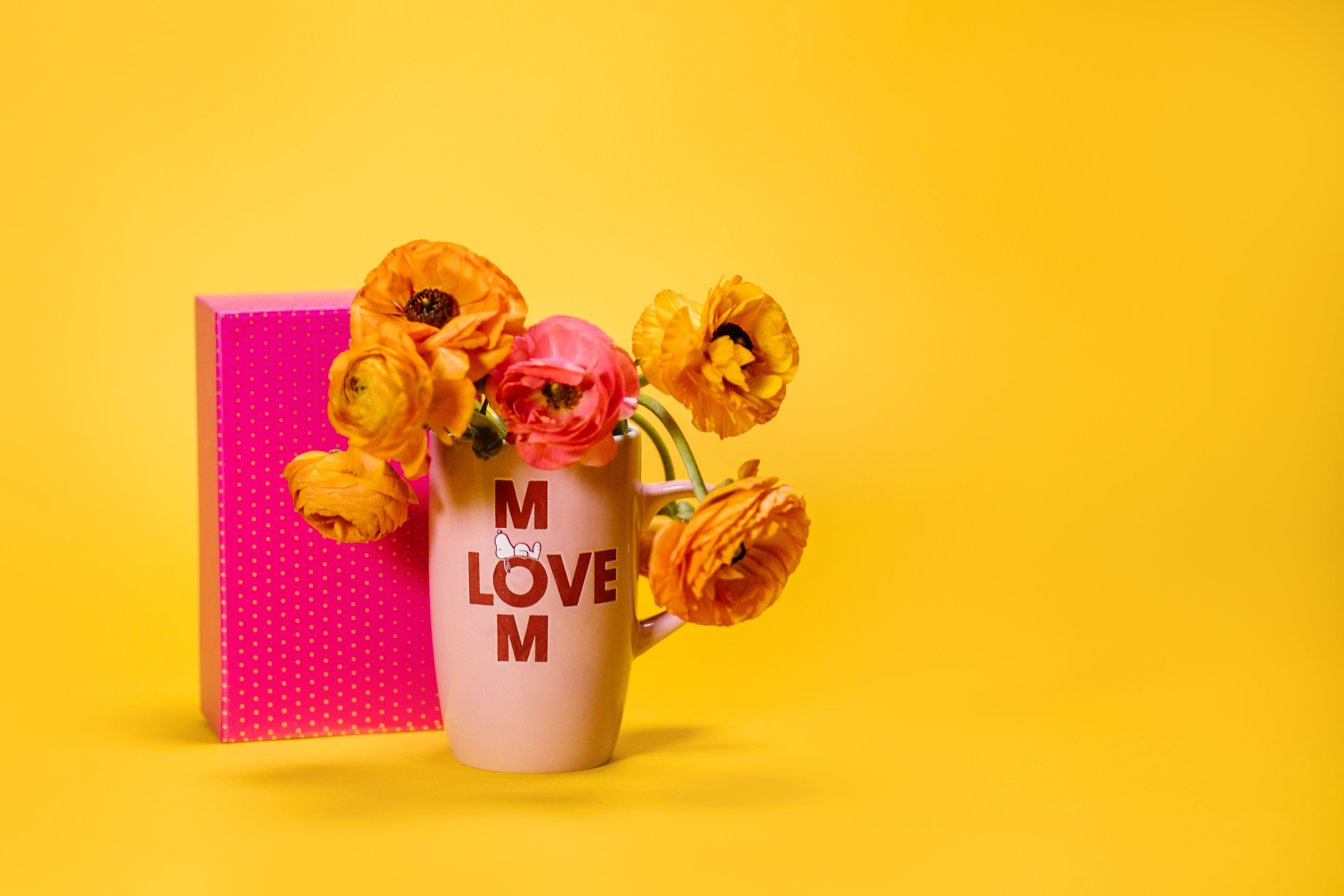 Colorful bouquet in a mom-themed mug on a bright yellow background, perfect for Mother's Day greetings.