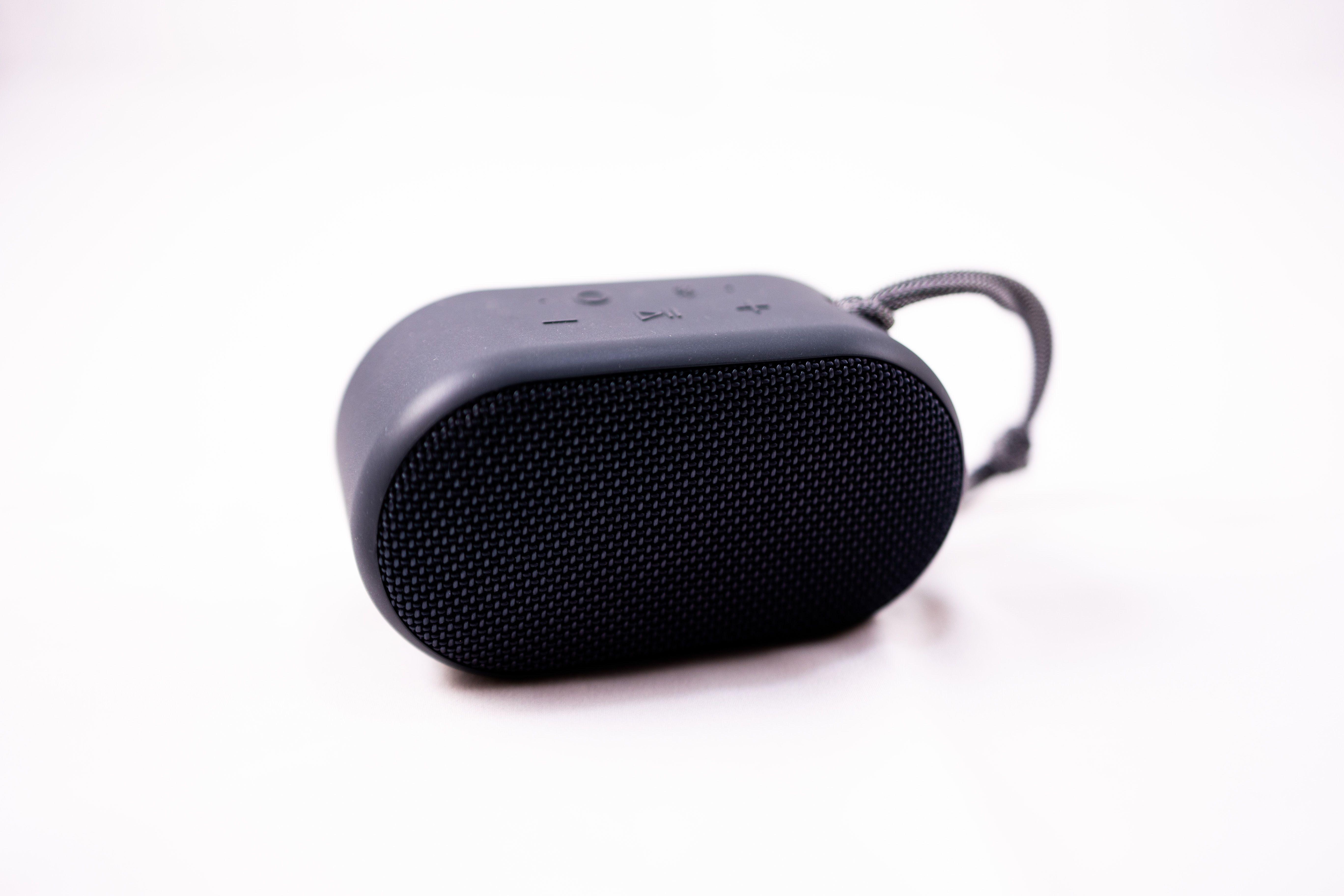 A stylish compact portable speaker with a textured exterior on a white background, showcasing modern technology.