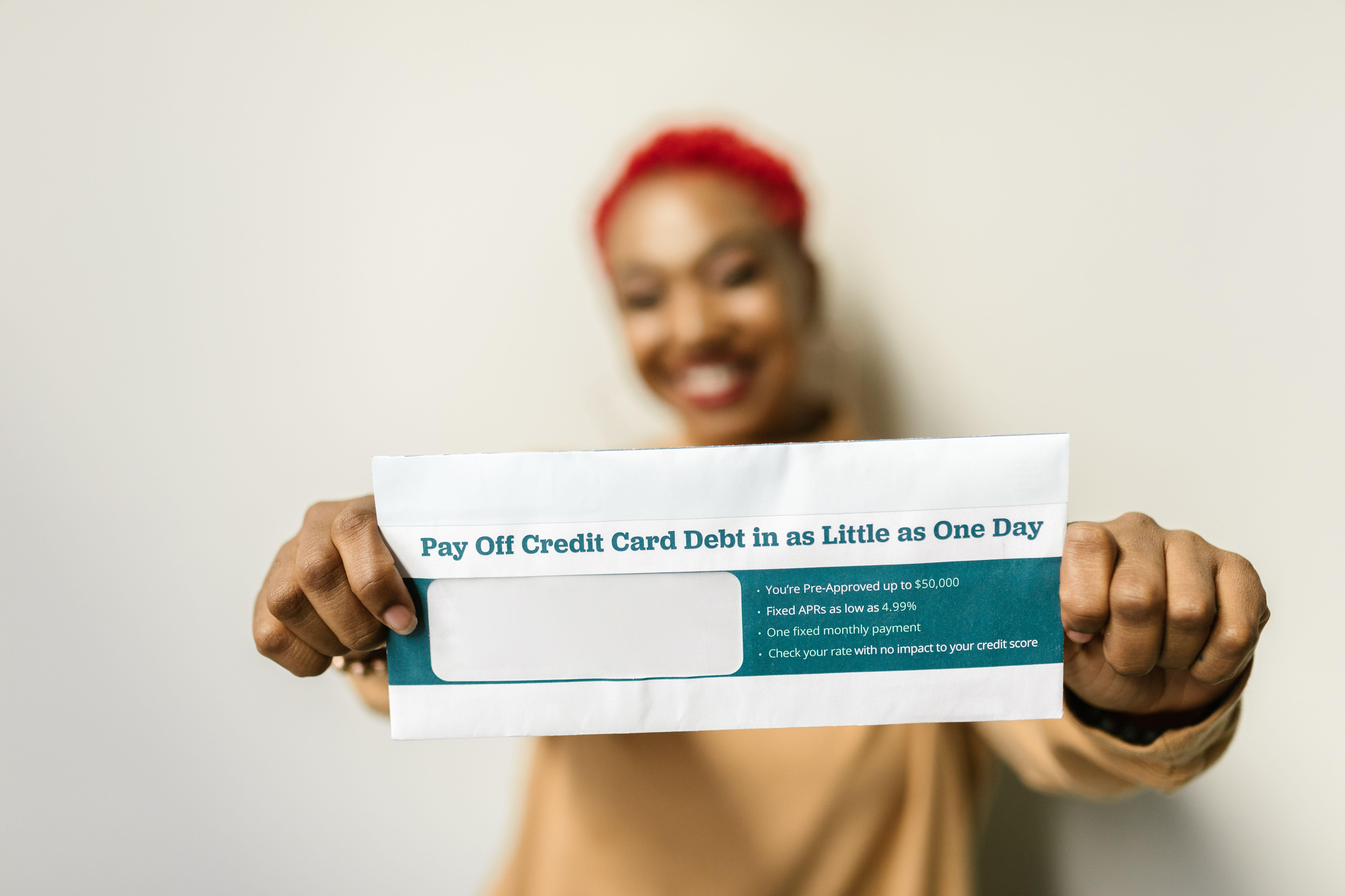 Woman presenting an envelope with a credit card debt offer, blurred background.
