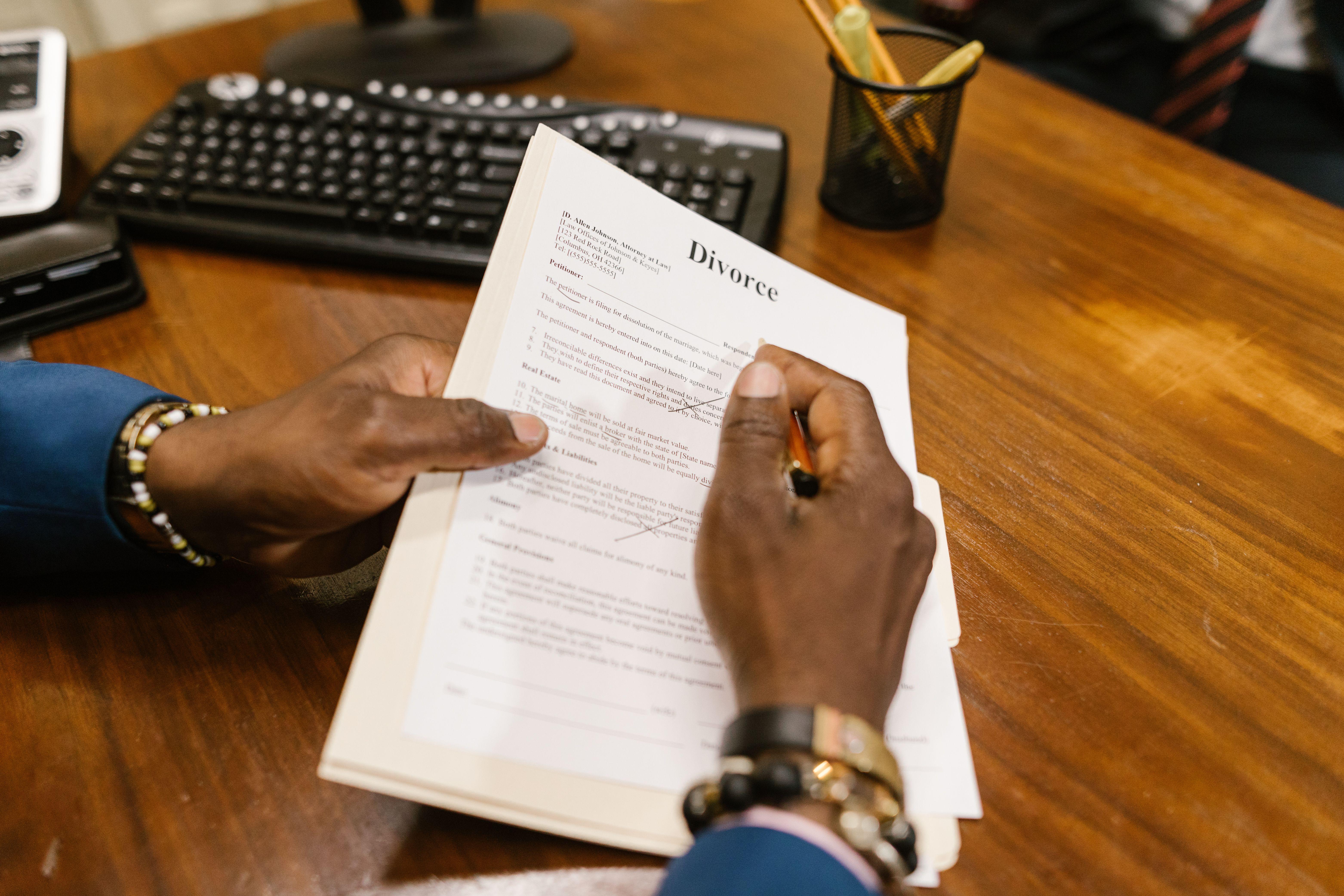 A person signs official divorce documents at an office desk.