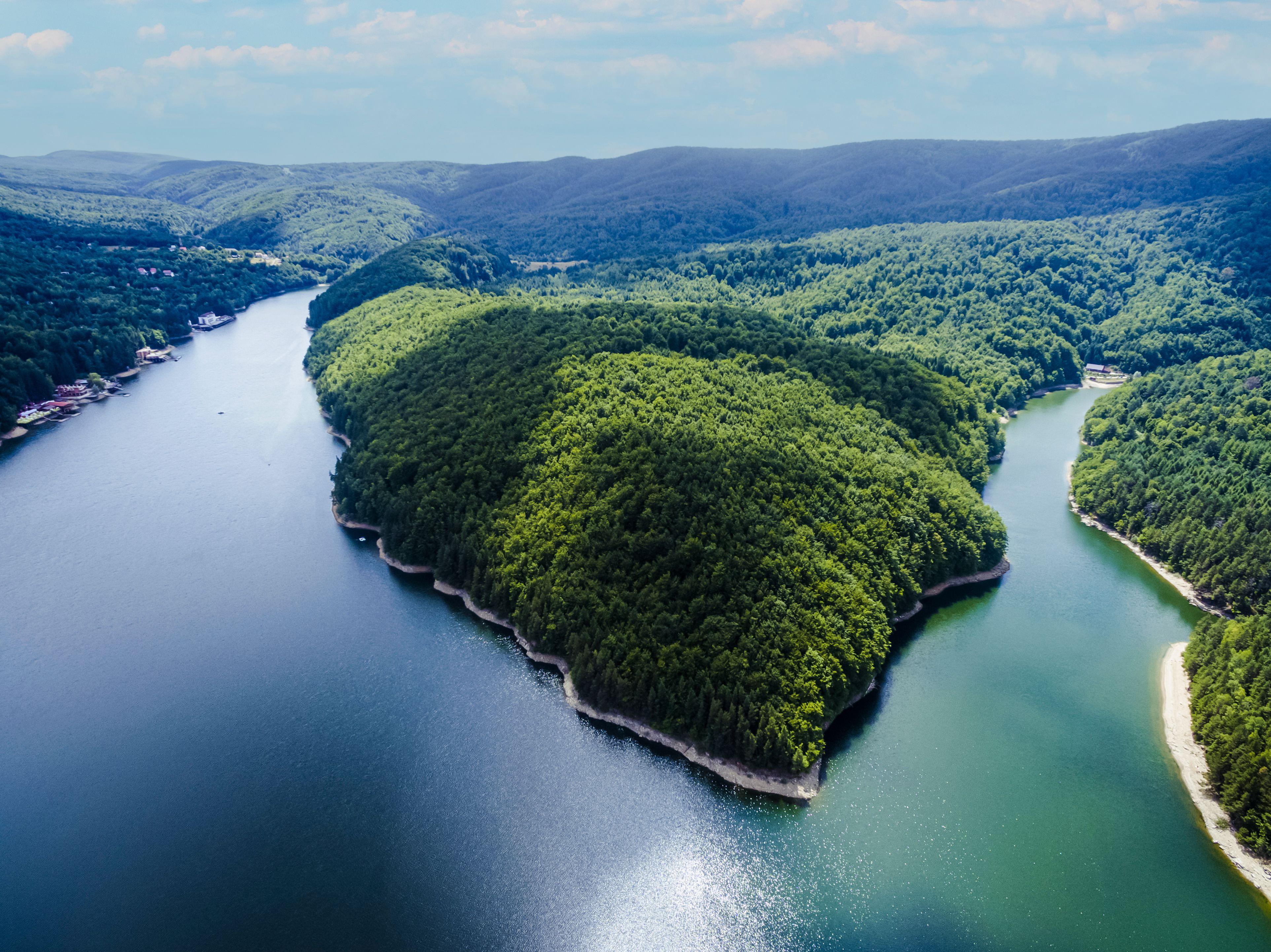 Stunning aerial view of Văliug Lake in Romania, showcasing lush greenery and serene waters.