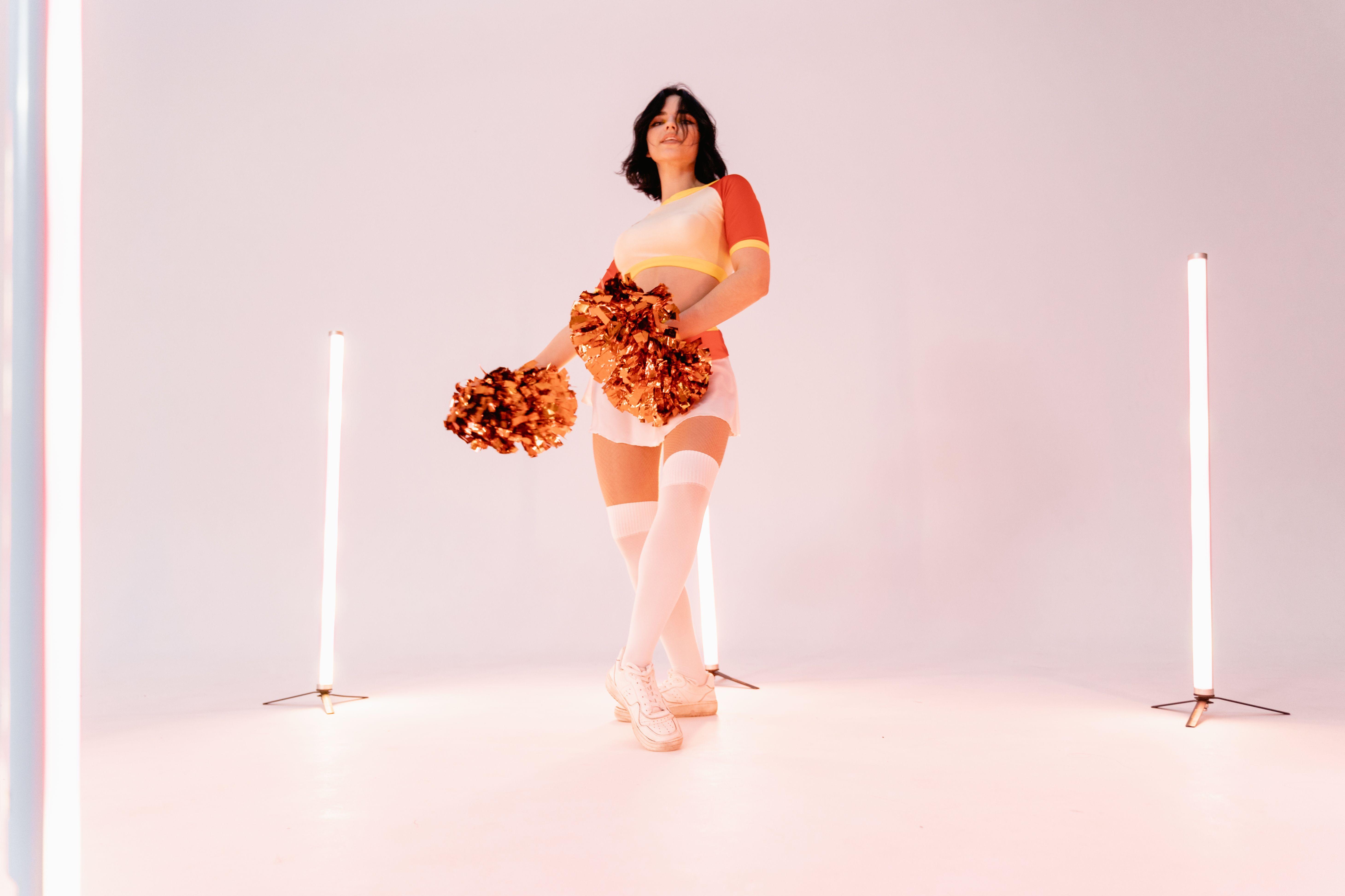 A vibrant studio shot of a female cheerleader with pompoms, expressing energy and fun.