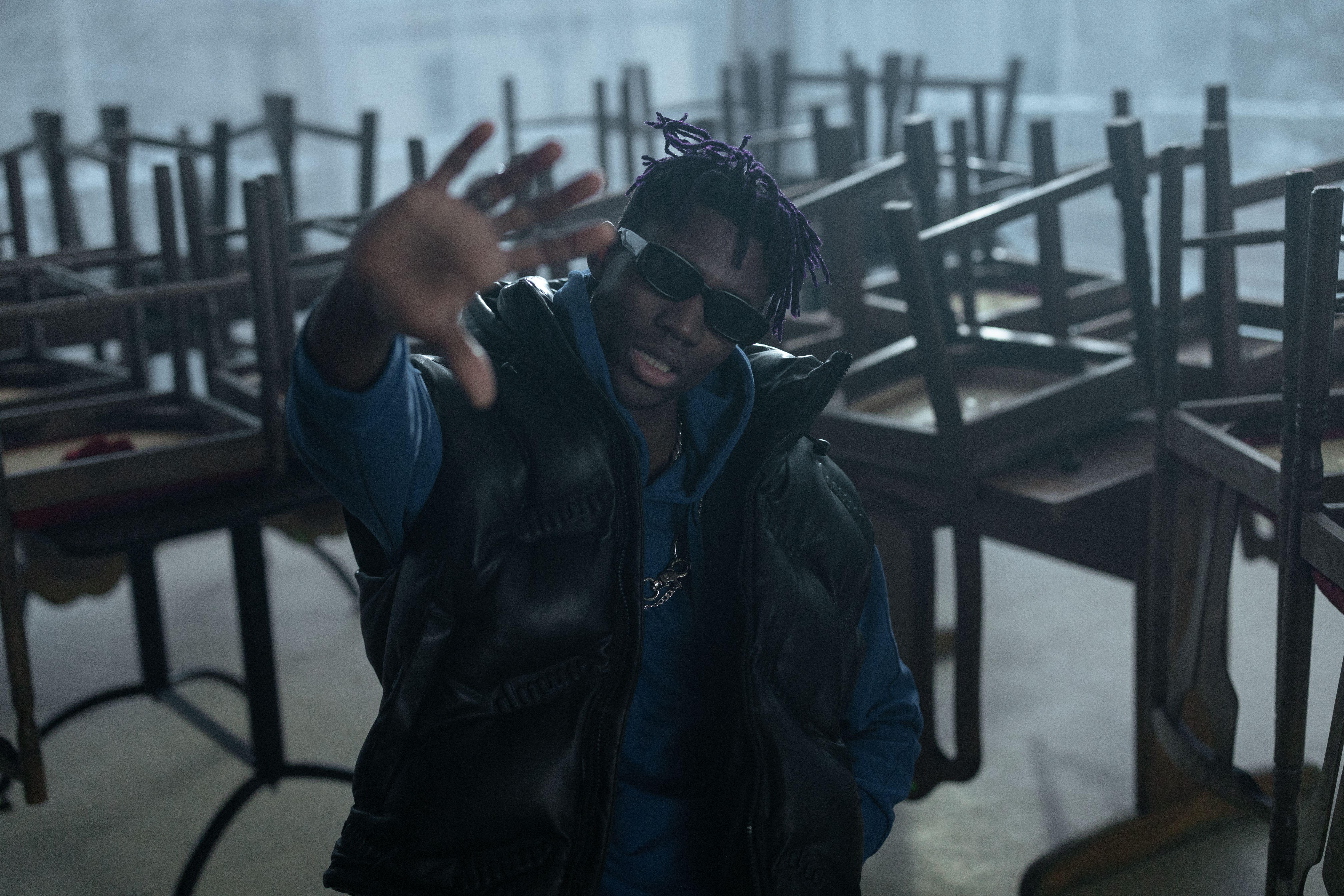A fashionable man in a puffer vest and sunglasses posing indoors. Captured with Canon EOS R.