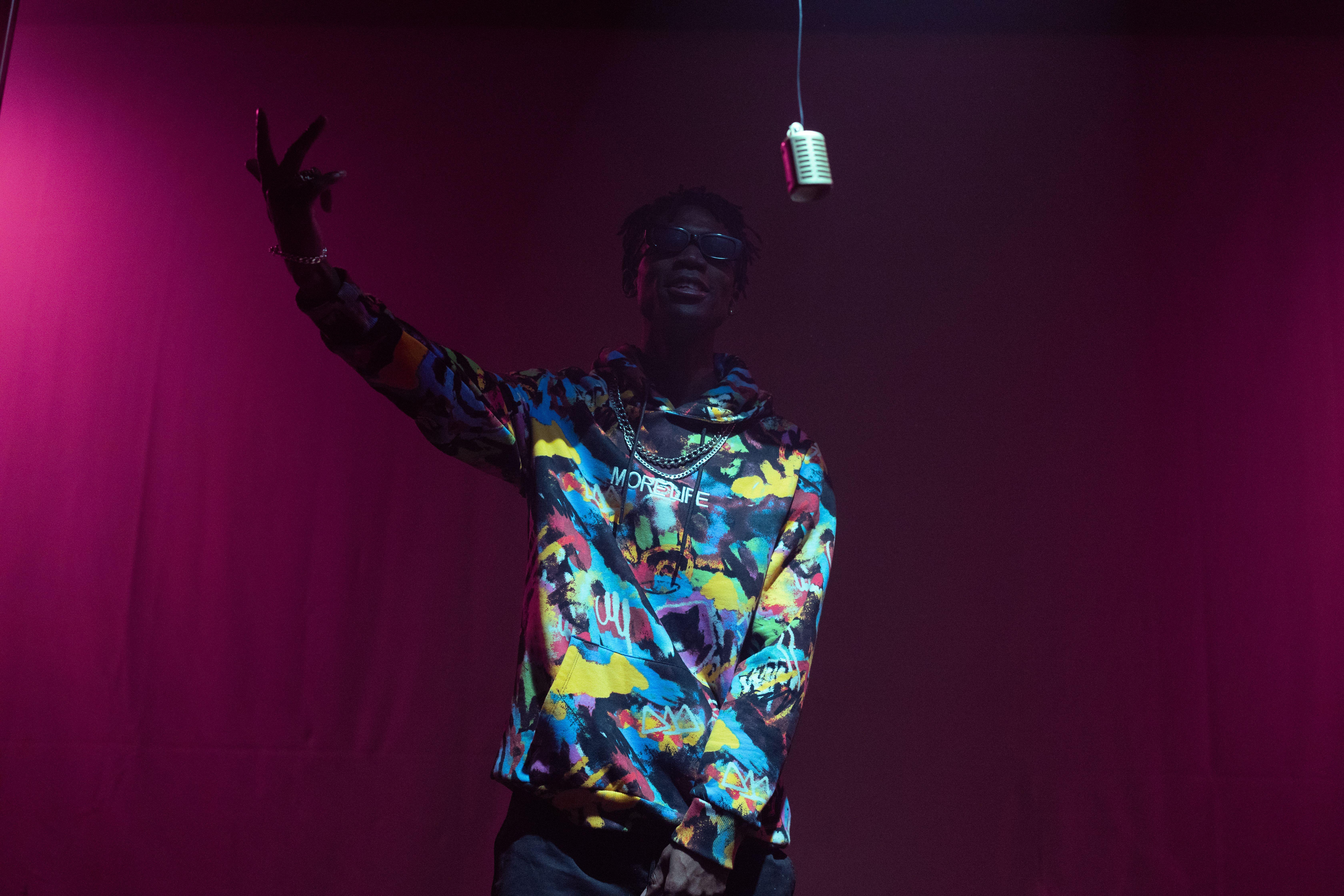 Engaging hip hop artist performing on stage with vintage microphone and vibrant fashion.