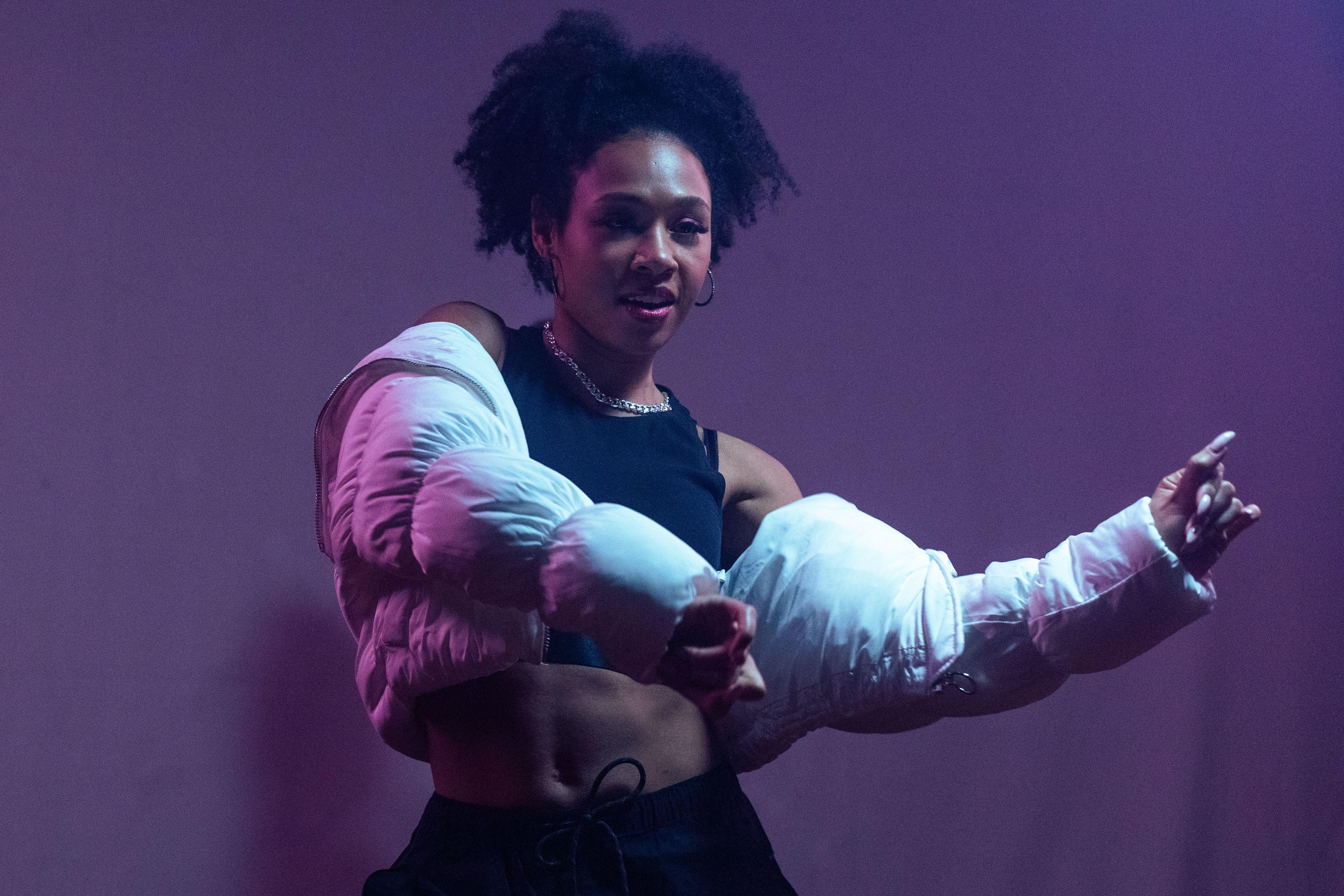 A dynamic African American woman performing hip hop dance moves in stylish attire.