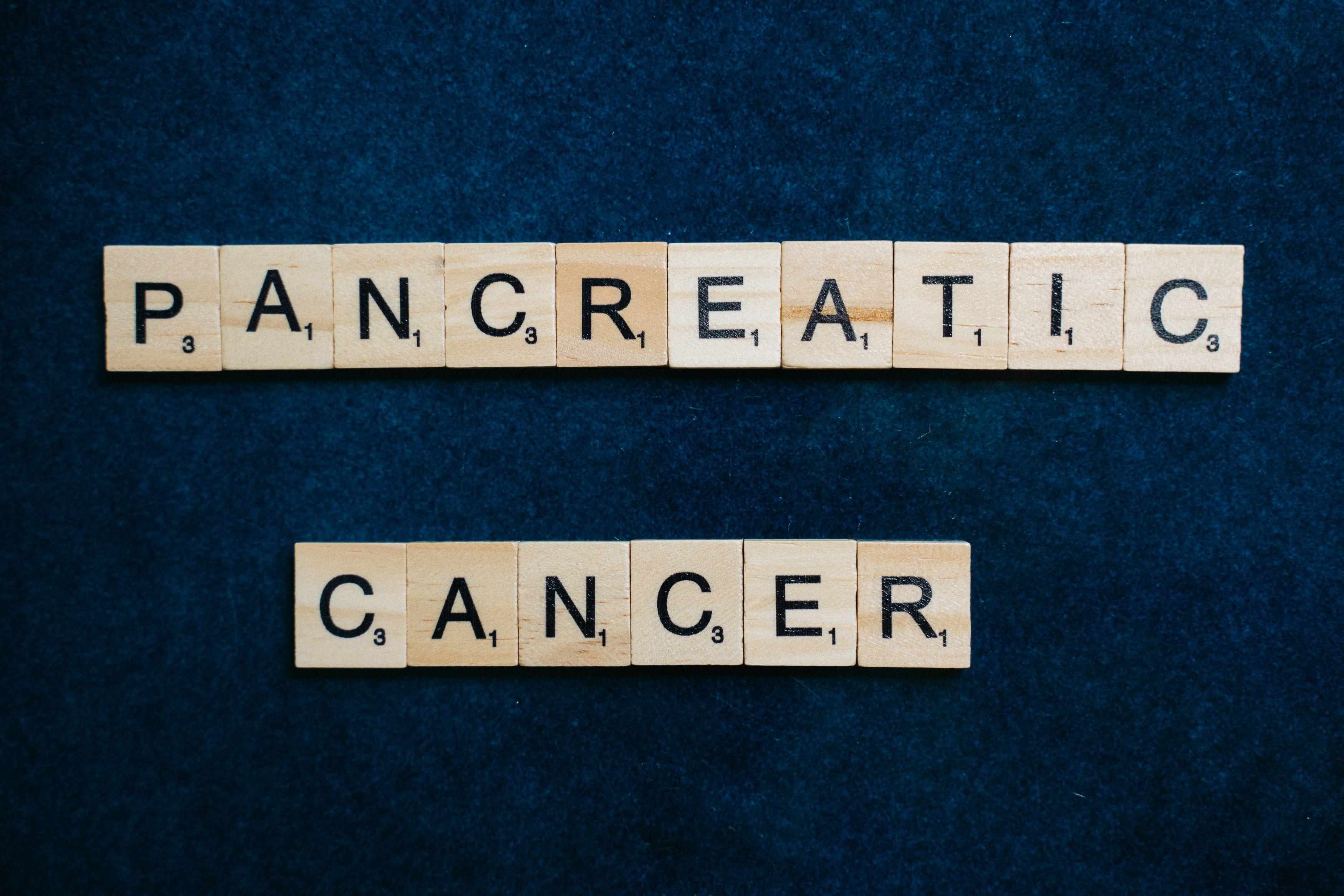 Wooden tiles spelling 'Pancreatic Cancer' on a textured blue background.
