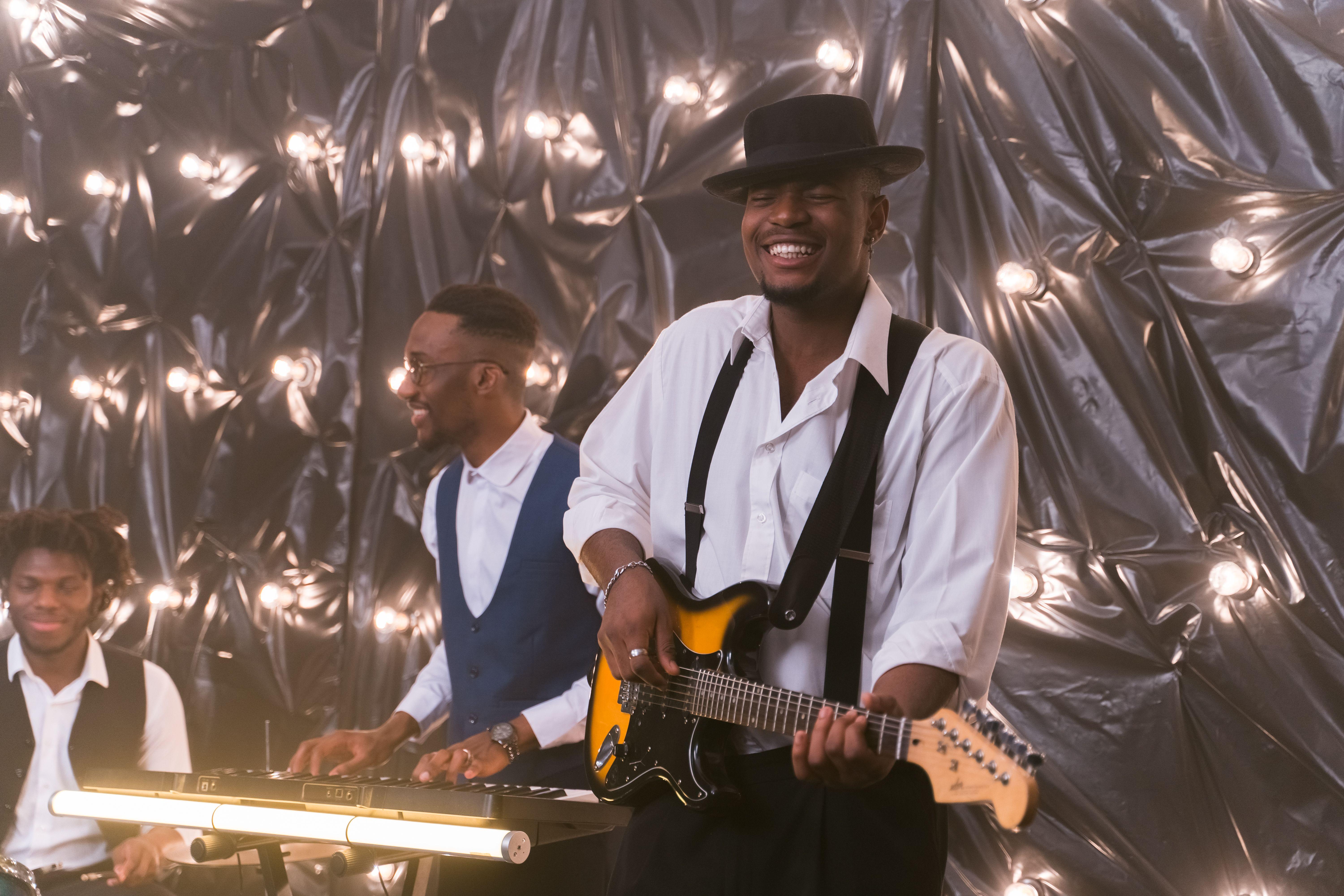 Lively music band performing with guitar and piano under stage lights.