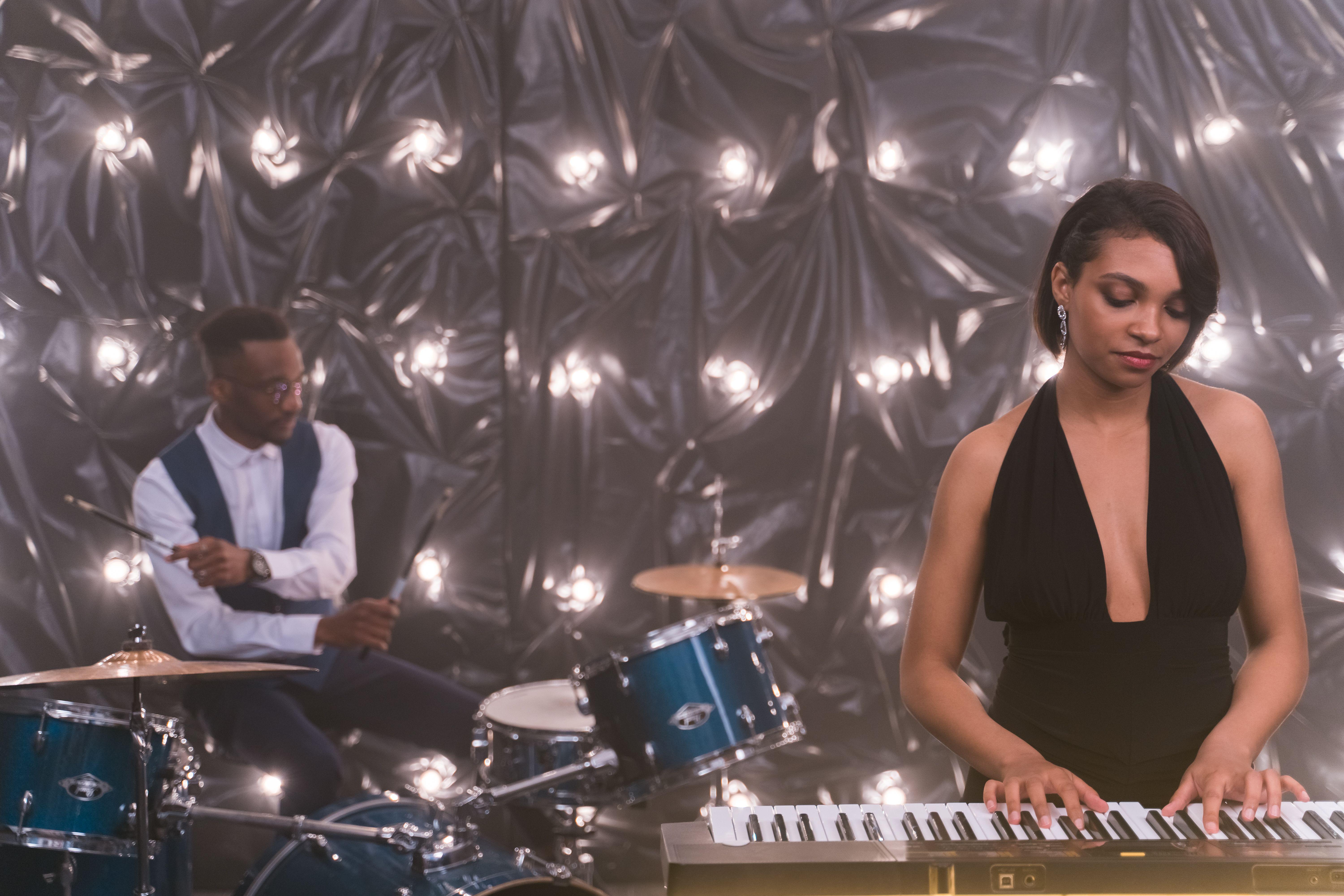 A jazz band featuring a pianist and drummer performing on stage with moody lighting.