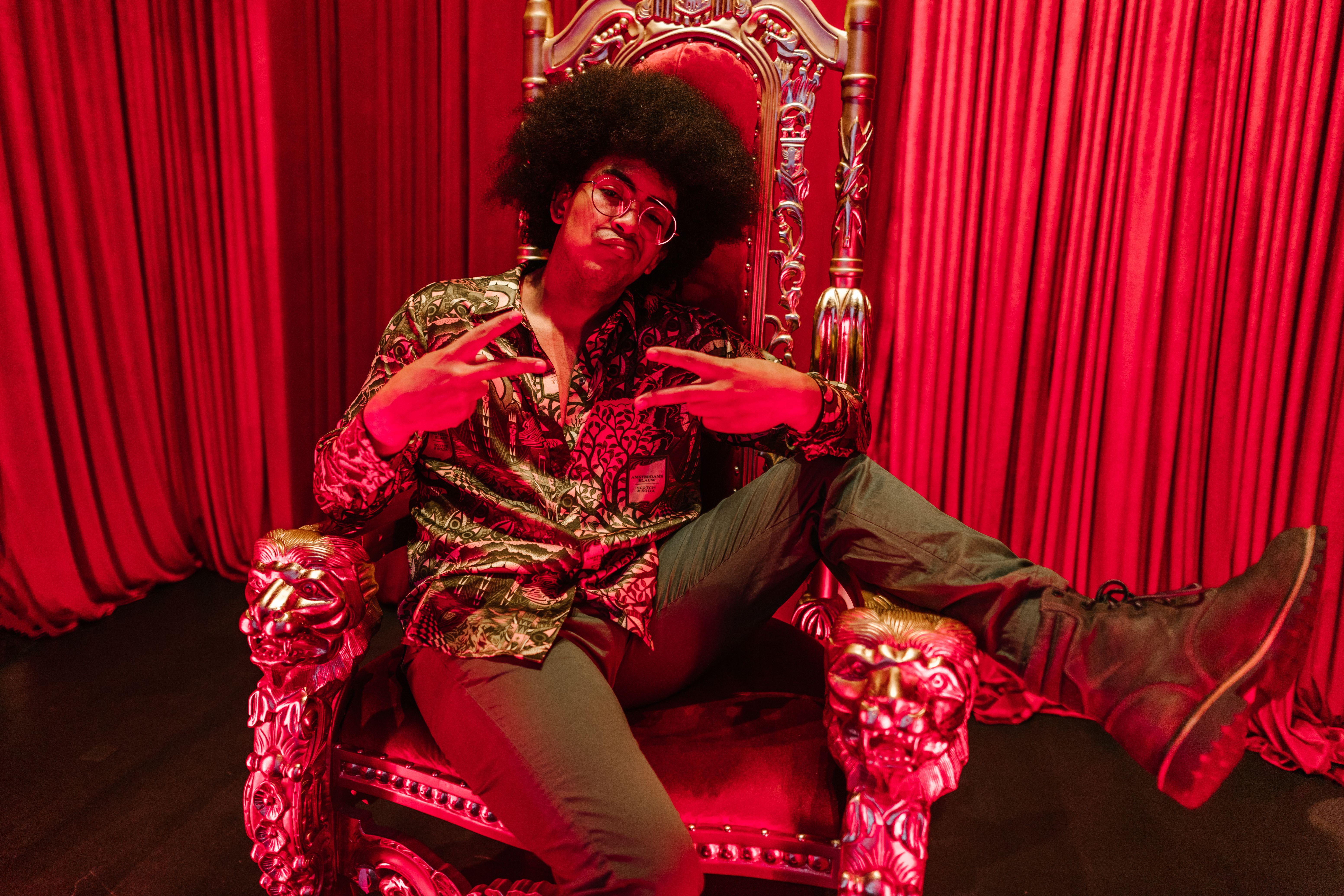 Stylish individual poses in luxurious setting with red velvet backdrop.