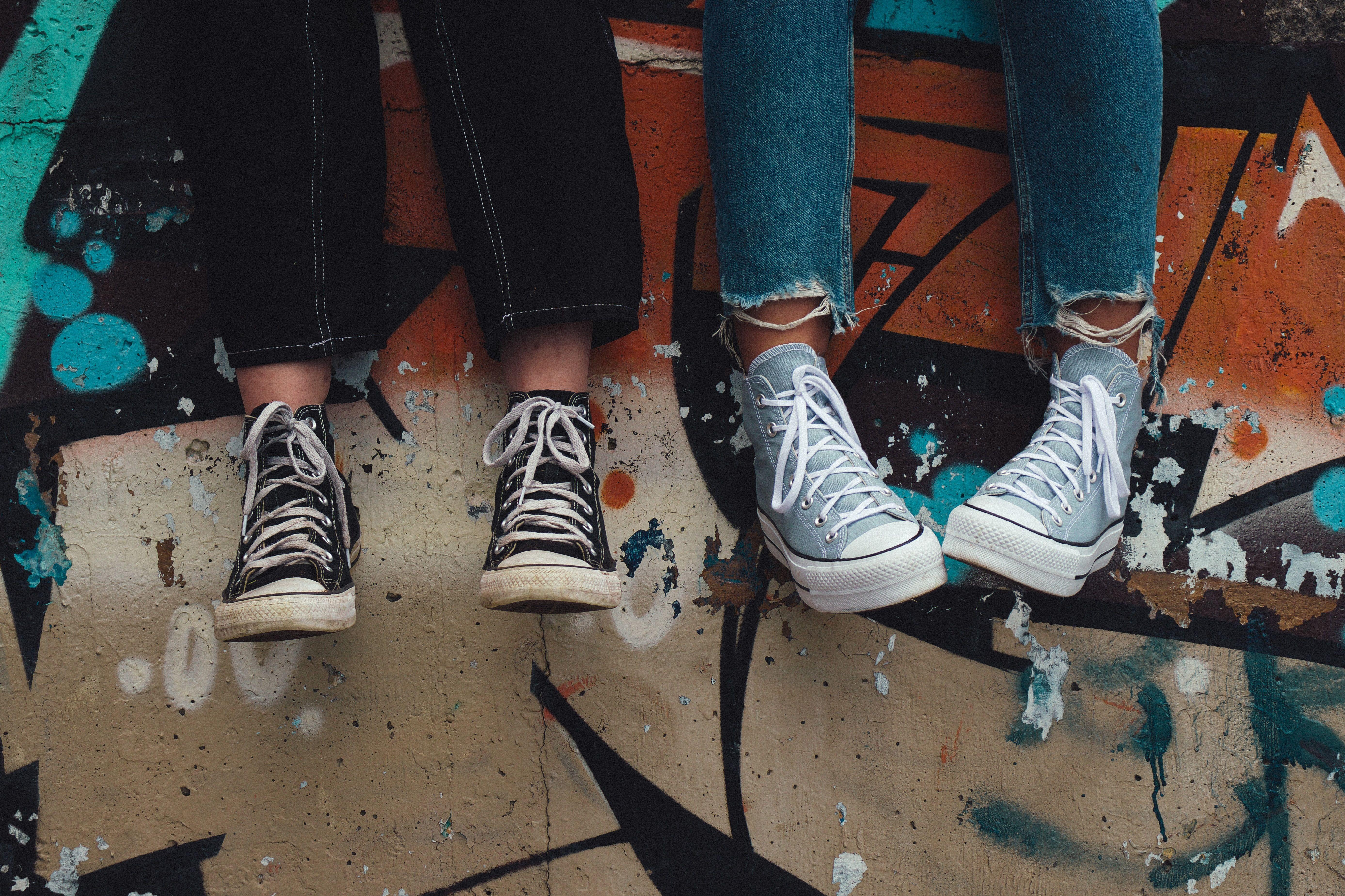 Two pairs of sneakers hanging over a graffiti wall, showcasing urban street style.