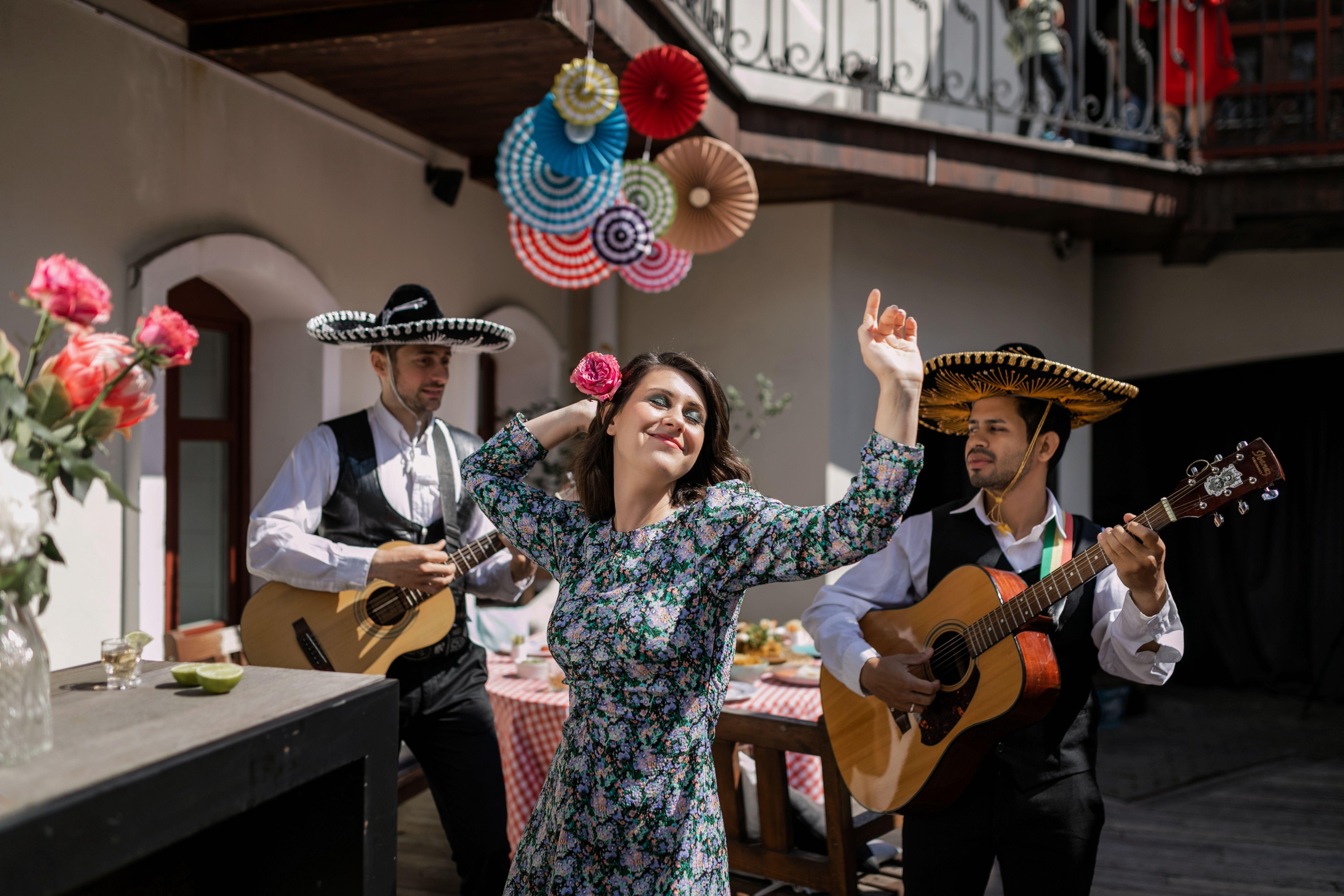 A lively scene with a woman dancing alongside mariachi musicians playing guitars.