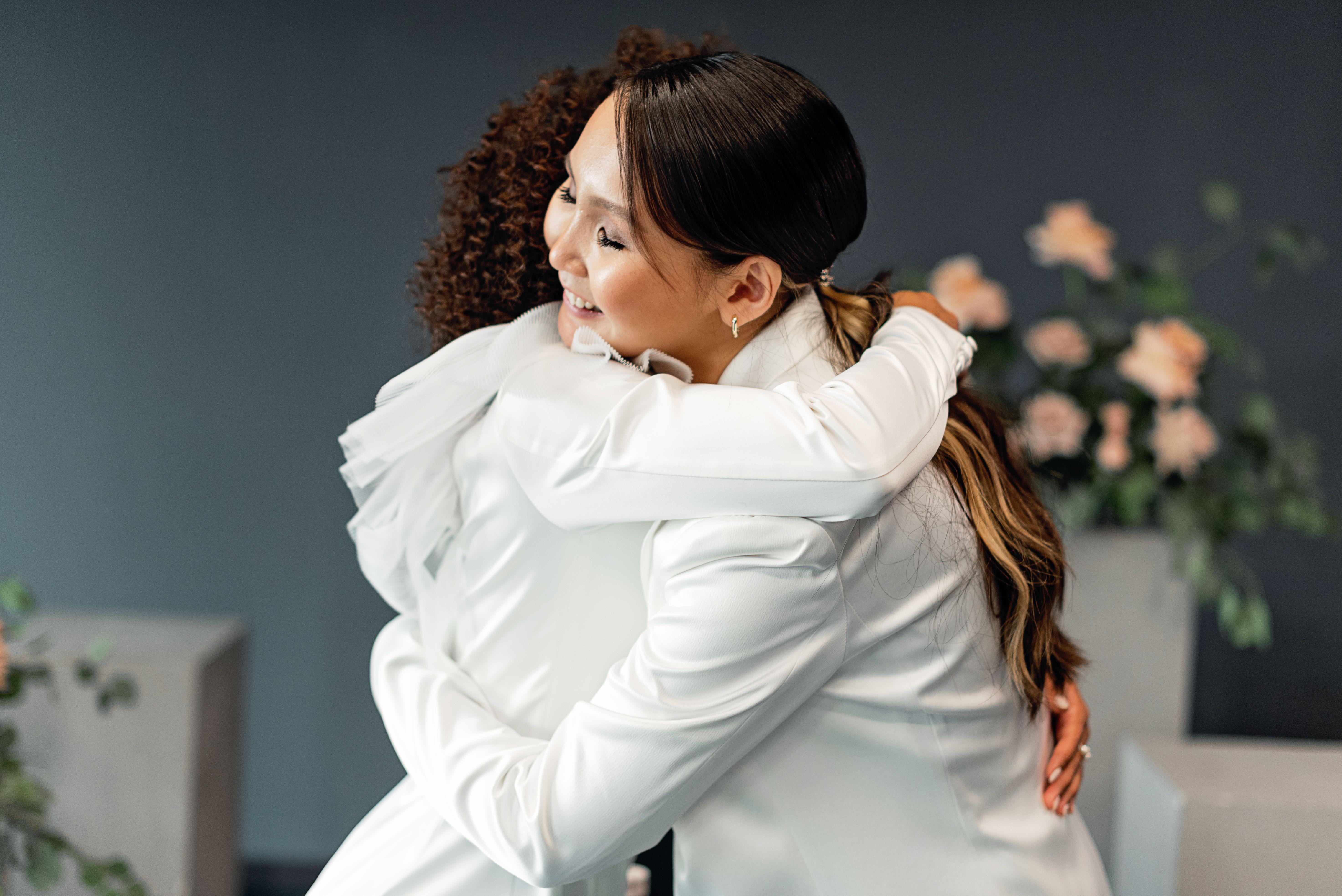 Two women embracing with joy, showcasing love and togetherness at a wedding.