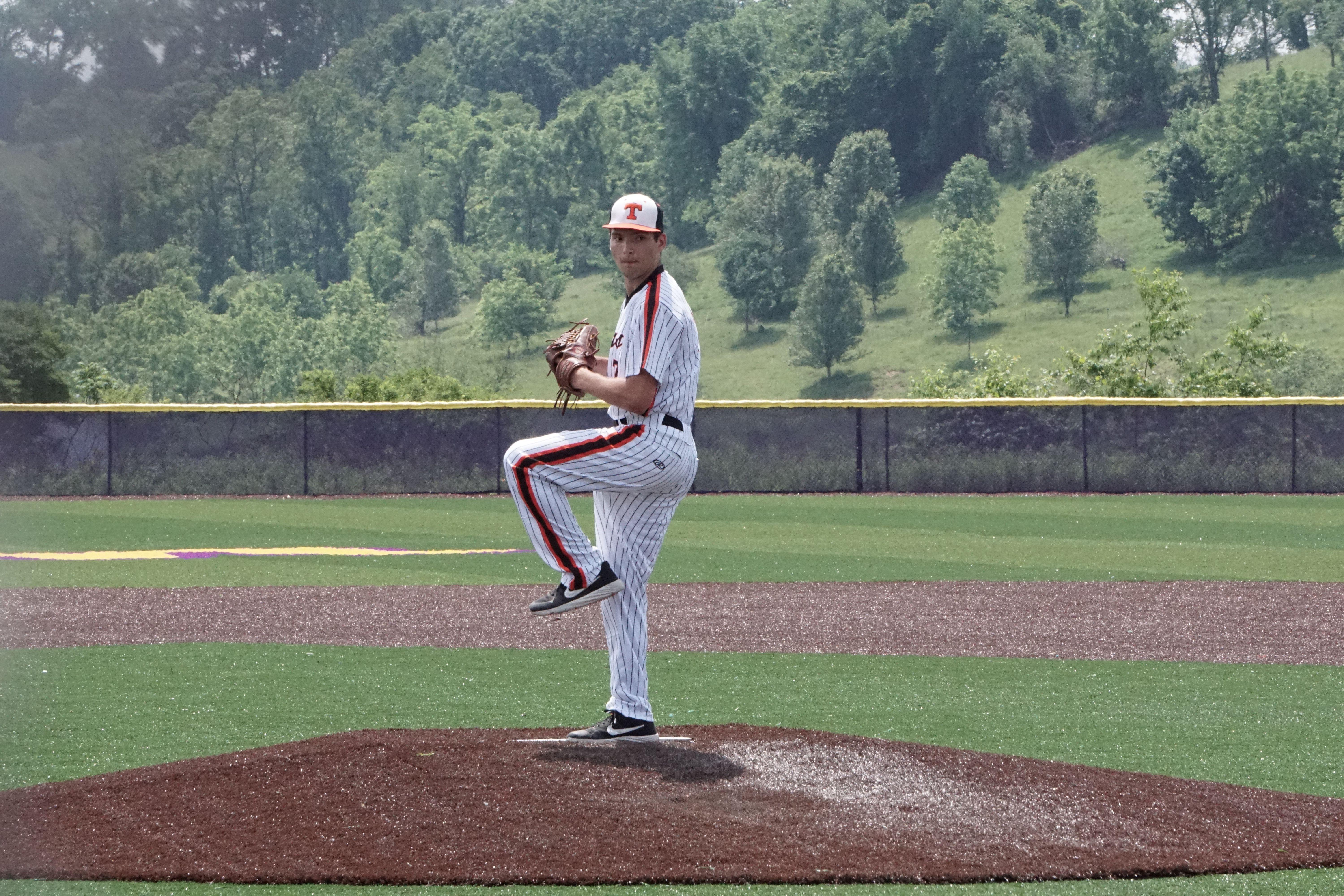 A baseball pitcher prepares to throw on a sunny day at an outdoor field.