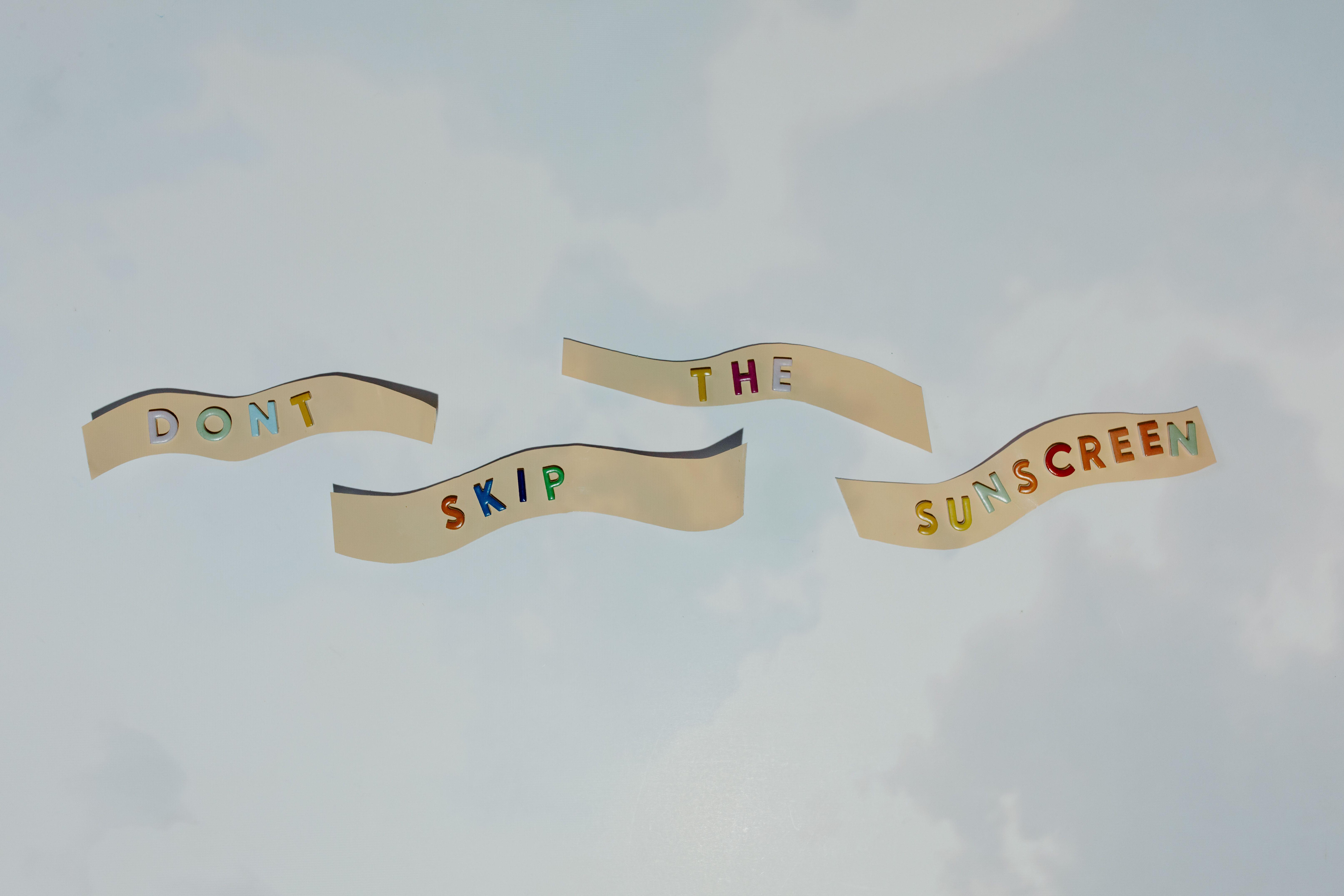 Colorful cutout letters forming a reminder to wear sunscreen against blue sky.