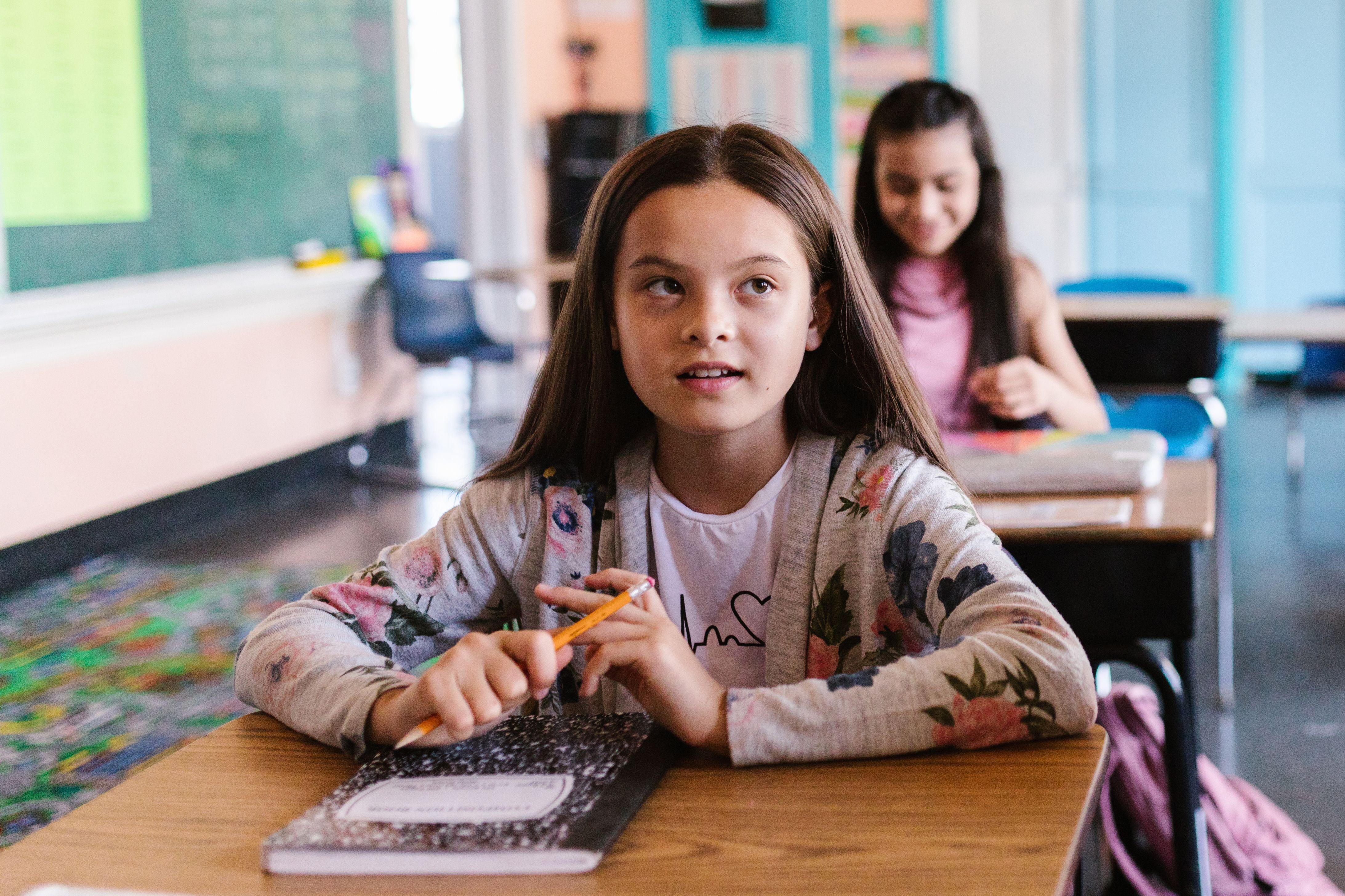 Two students attentively participate in a classroom environment, showcasing a back-to-school theme.