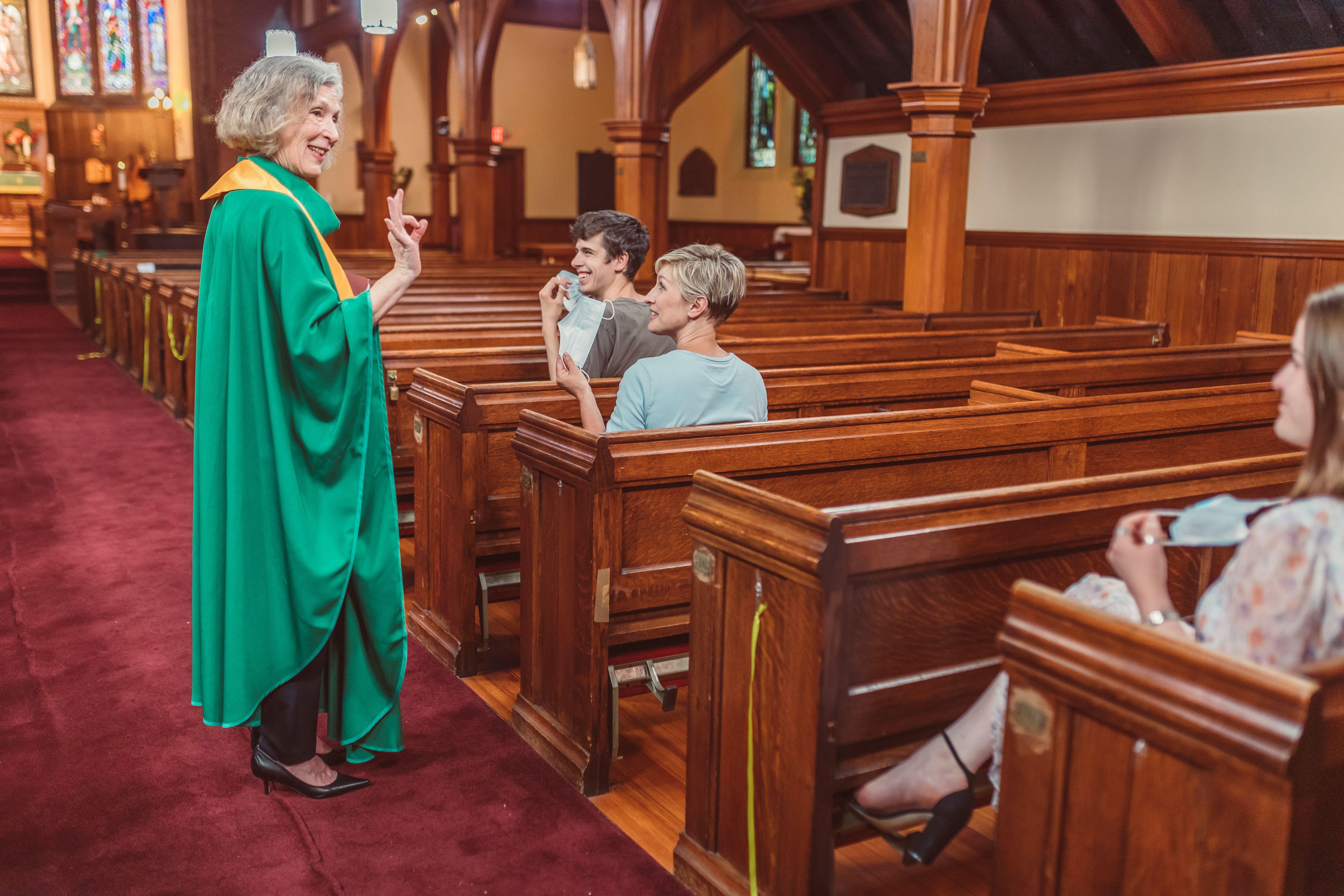 A priest interacts with parishioners inside a church, emphasizing community spirit.