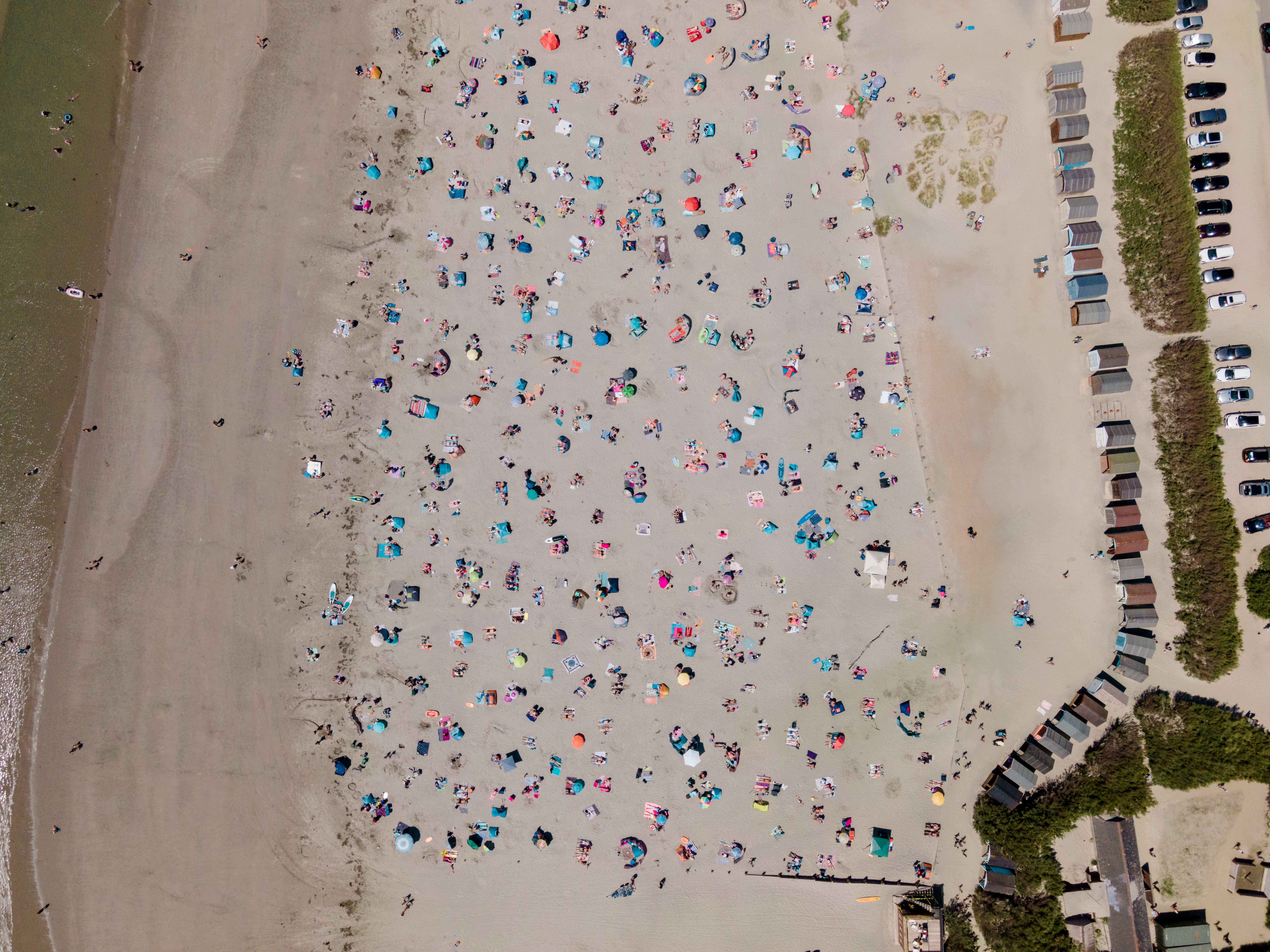 A bird's eye view of West Wittering beach in England, bustling with people on a sunny day.