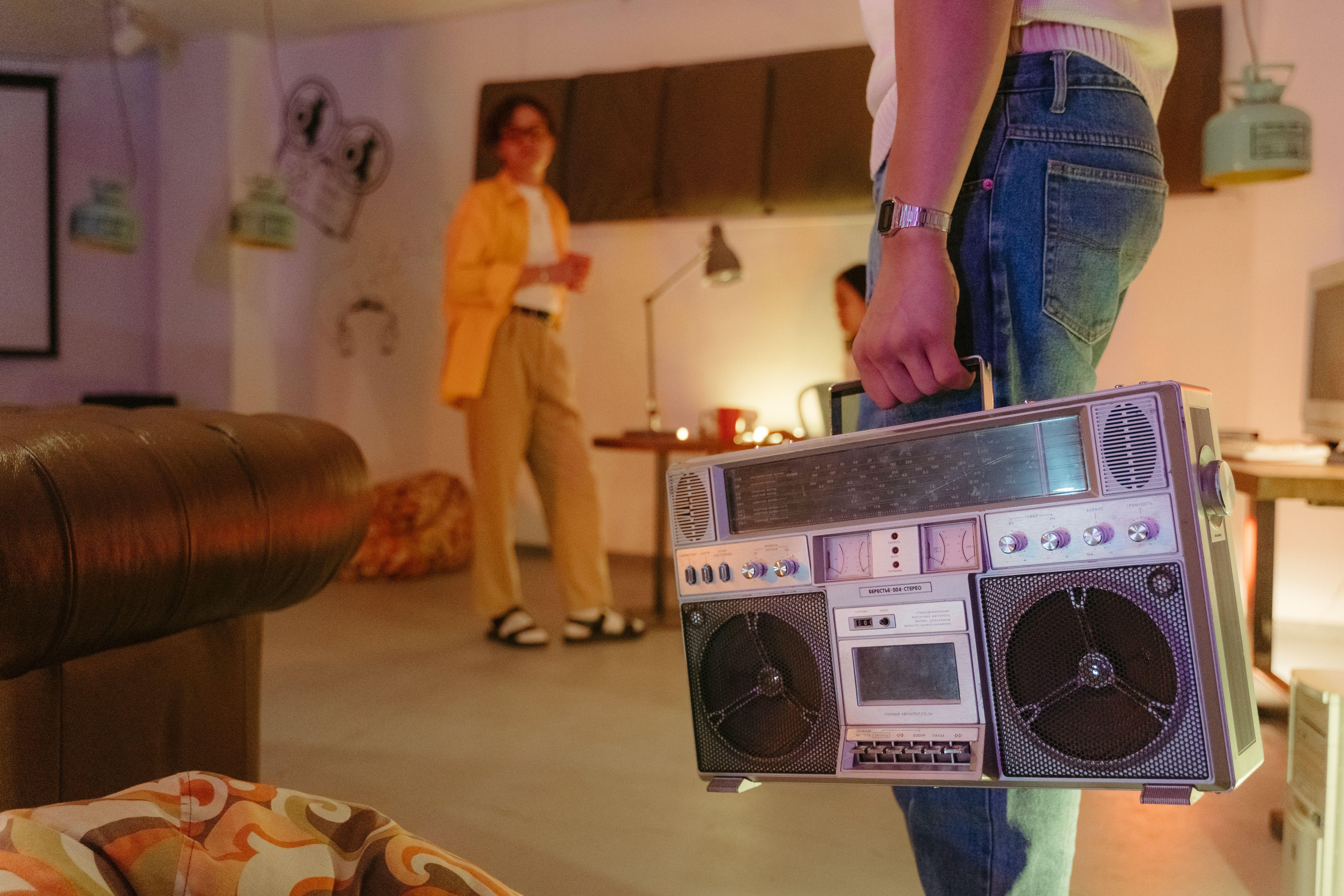 A person holding a vintage boombox in a stylish retro-themed room, showcasing a nostalgic vibe.