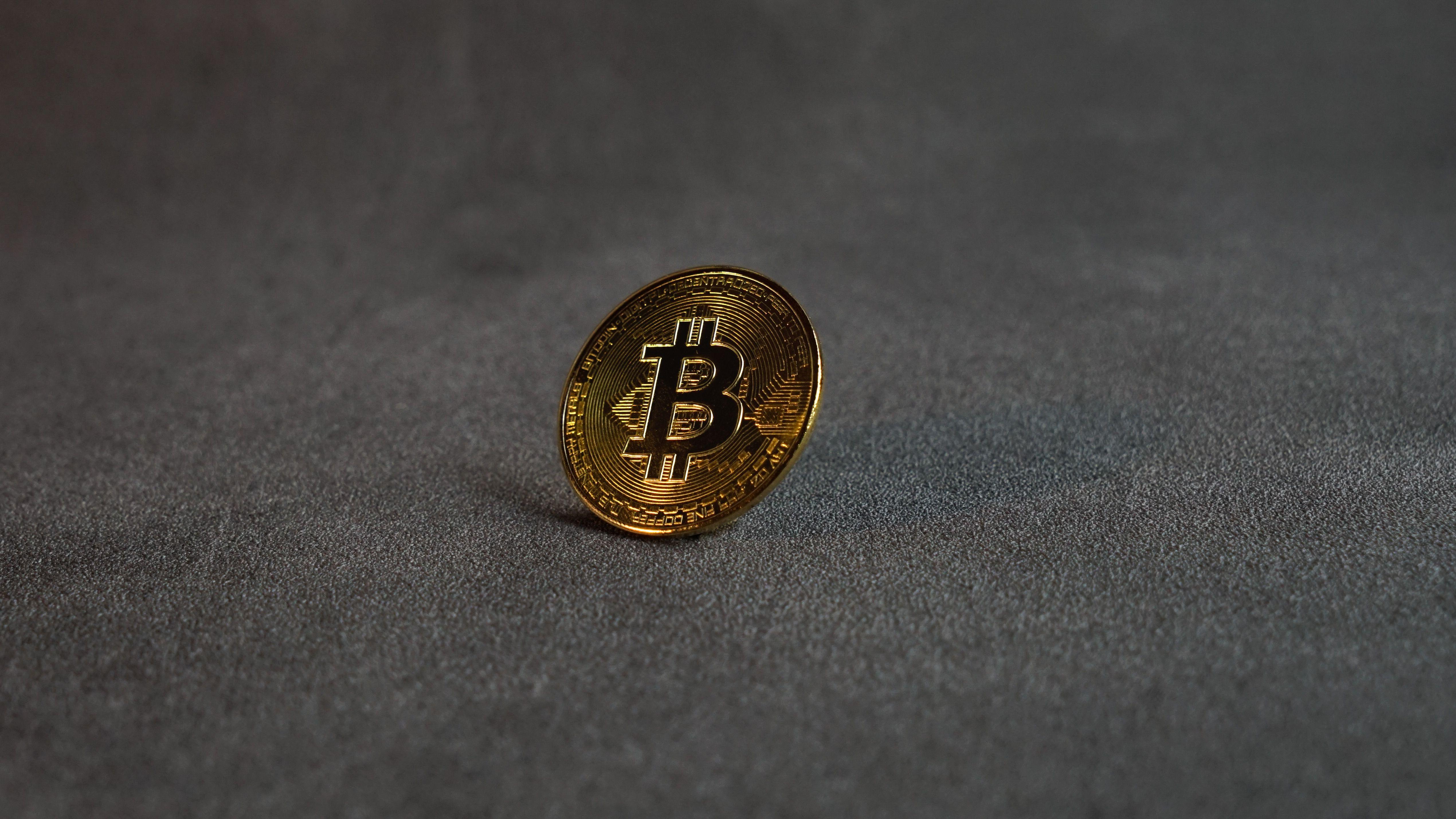 Close-up image of a golden Bitcoin standing on a grey surface, symbolizing cryptocurrency and digital finance.