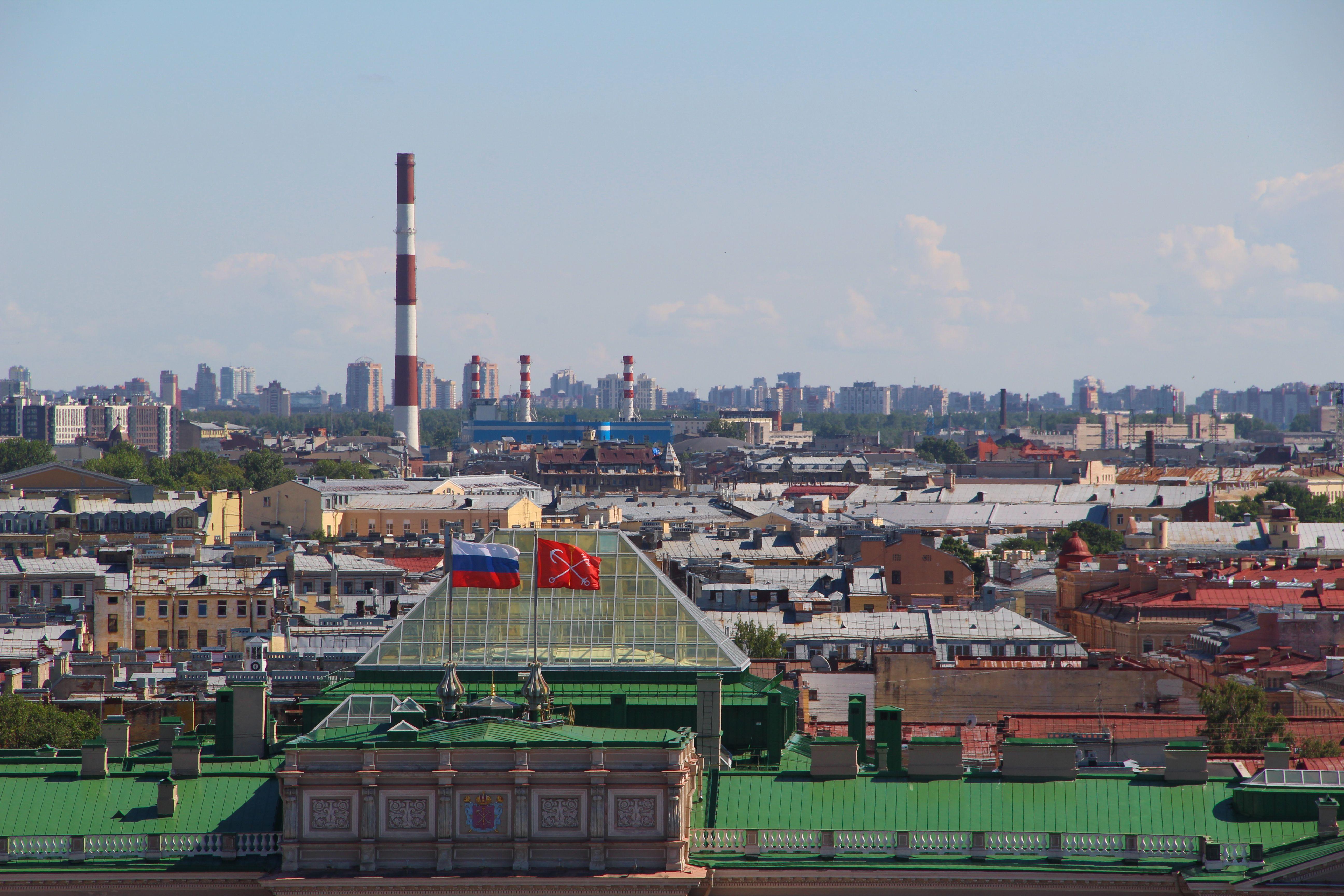 Breathtaking aerial view of urban Saint Petersburg skyline with chimneys and flags.