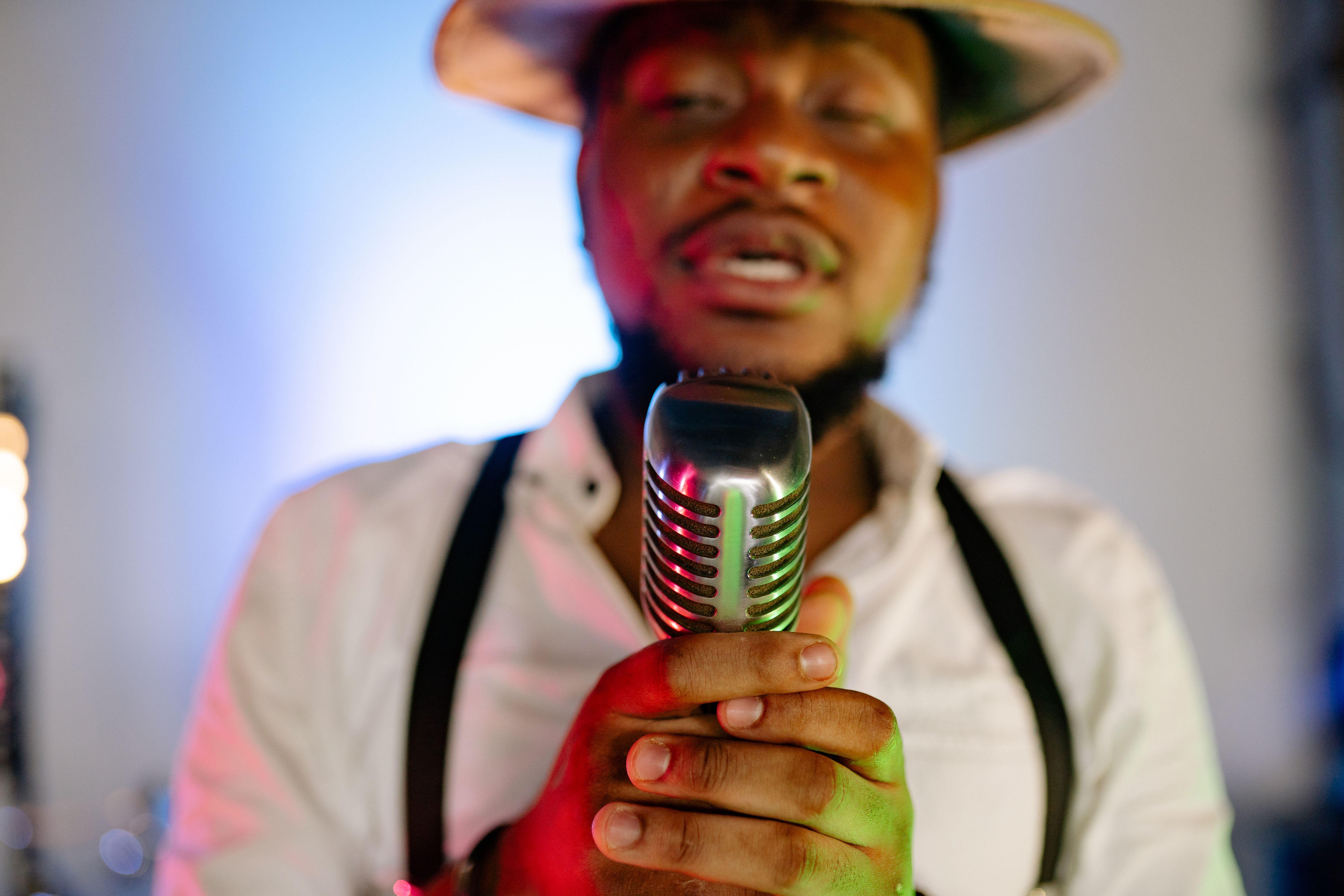 Close-up of a male singer holding a vintage microphone in a studio setting.