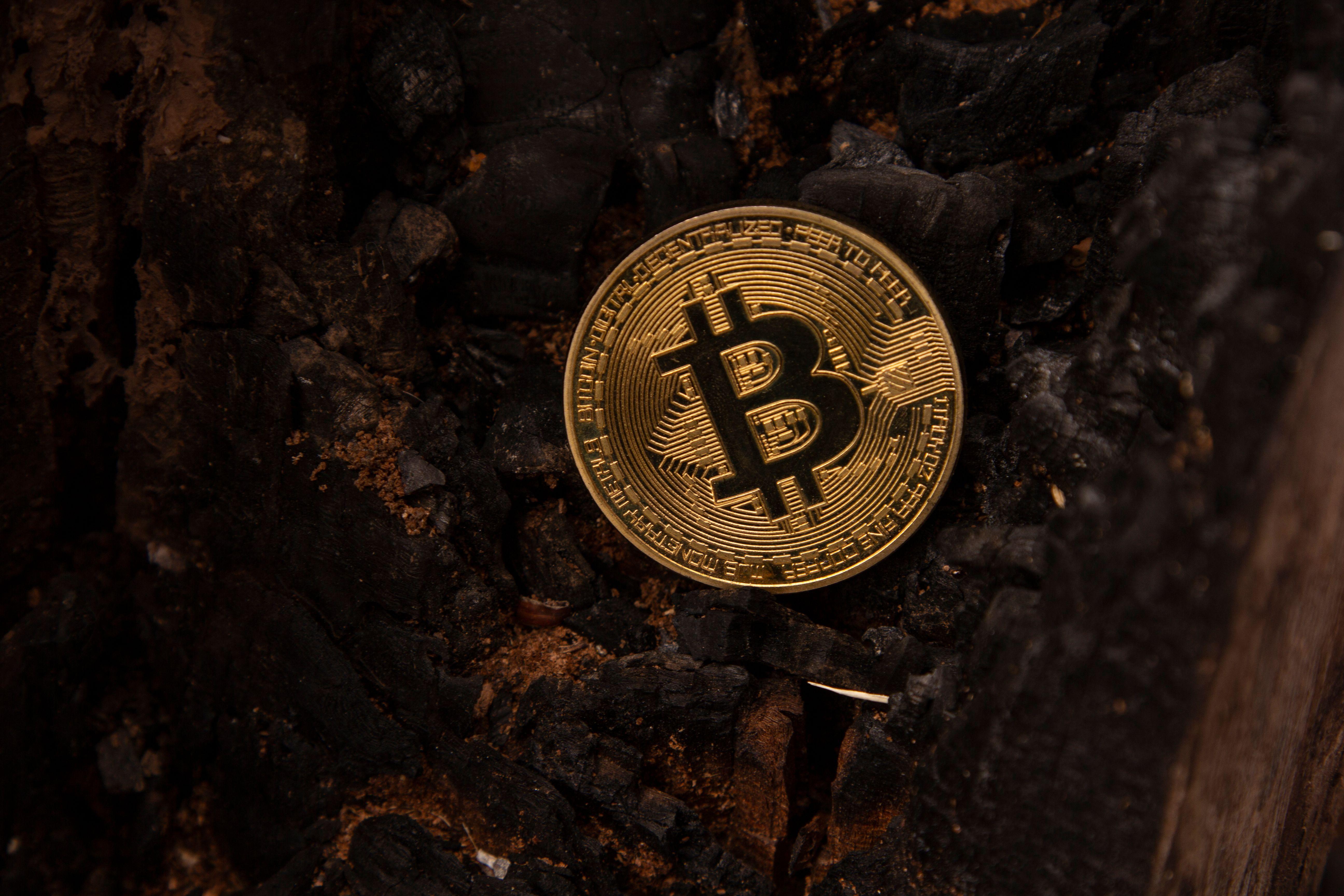 Detailed image of a Bitcoin coin placed on a charred, burnt background, symbolizing the rise of cryptocurrency.