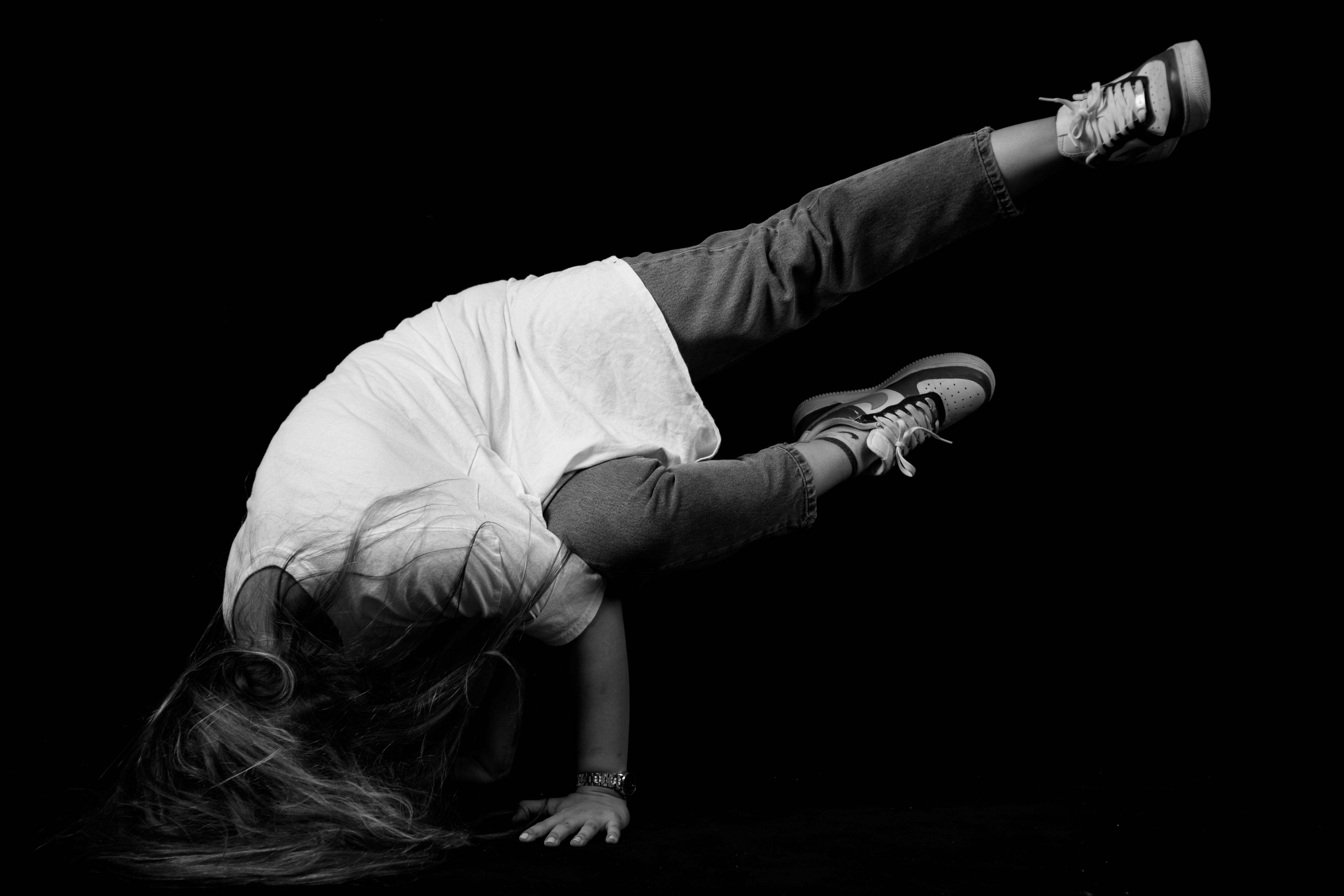 Energetic breakdancer in headstand pose against a dark backdrop.