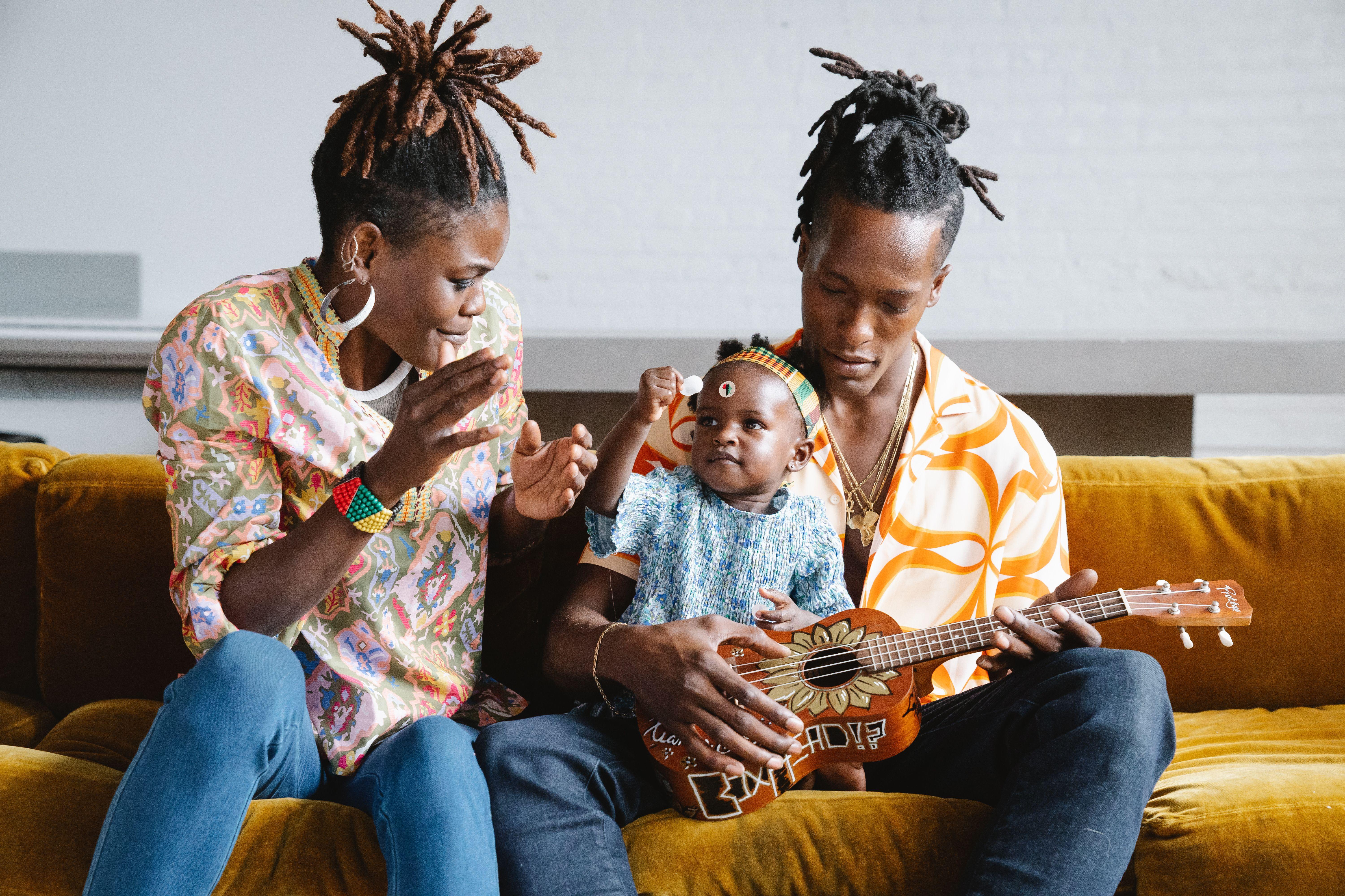 A joyful family moment with parents and child enjoying music and laughter.