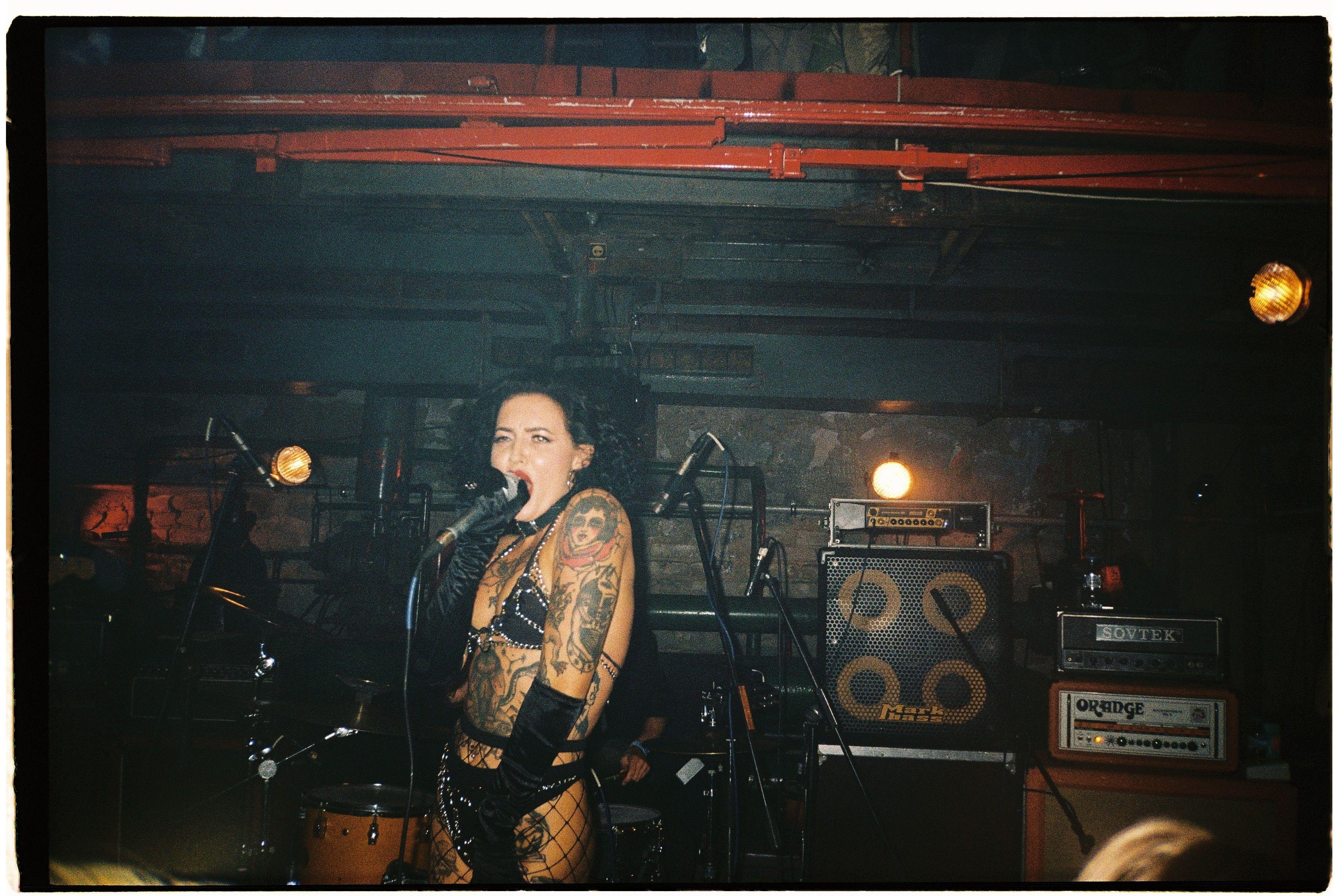 Tattooed female punk singer performing energetically on stage at a concert.