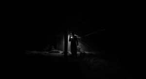 A shadowy figure explores a dimly lit, eerie attic with a flashlight.