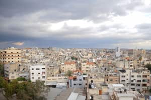 Aerial view of Qalqilya's urban cityscape under dramatic clouds, showcasing diverse architecture.