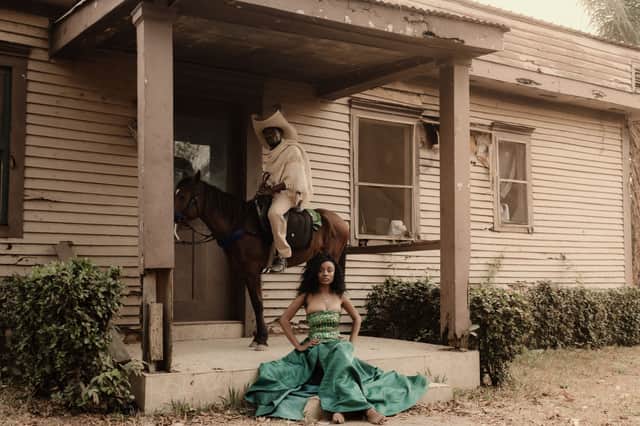 Man on horseback and woman in traditional dress outside a rustic building in Nigeria.