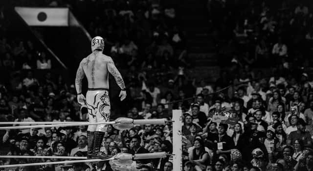 Dramatic black and white shot of a masked wrestler in action before an excited crowd in Ciudad de México.