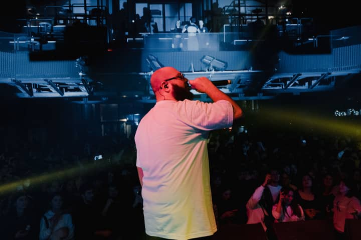 A dynamic rapper captivates the audience under vibrant stage lights during a live concert.