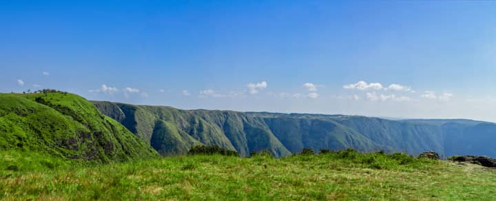 Stunning panoramic view of Meghalaya's lush green hill ranges under a clear blue sky.