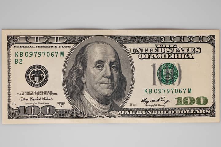 A detailed close-up of a US $100 bill featuring Benjamin Franklin on a white background.