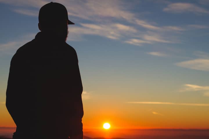 A silhouette of a man against a vibrant sunrise sky, symbolizing solitude and introspection.