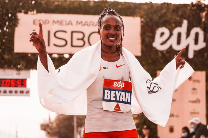 A female athlete celebrates her marathon victory with a champion's pose.