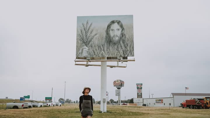 A person stands under the famous Wheat Jesus billboard along a highway in Colby, Kansas.