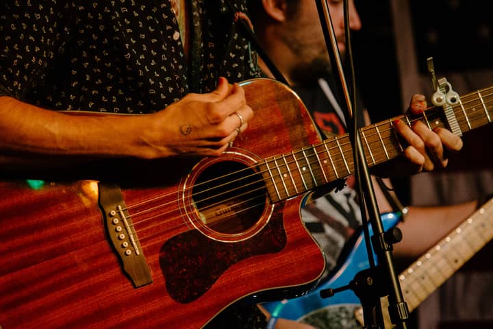 Hands playing an acoustic guitar during a live music performance in Boston.