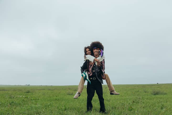 A cheerful couple enjoying a playful piggyback ride in a serene grass field.